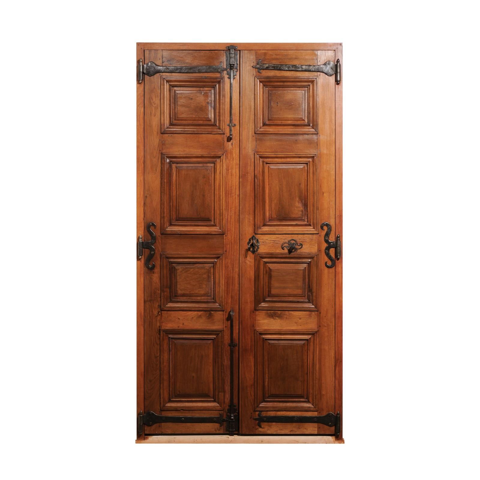 A pair of French Régence period walnut communication doors from the second quarter of the 18th century, with raised panels and iron hardware. Created in France during short Régence period which saw the transition of power between the Sun King and