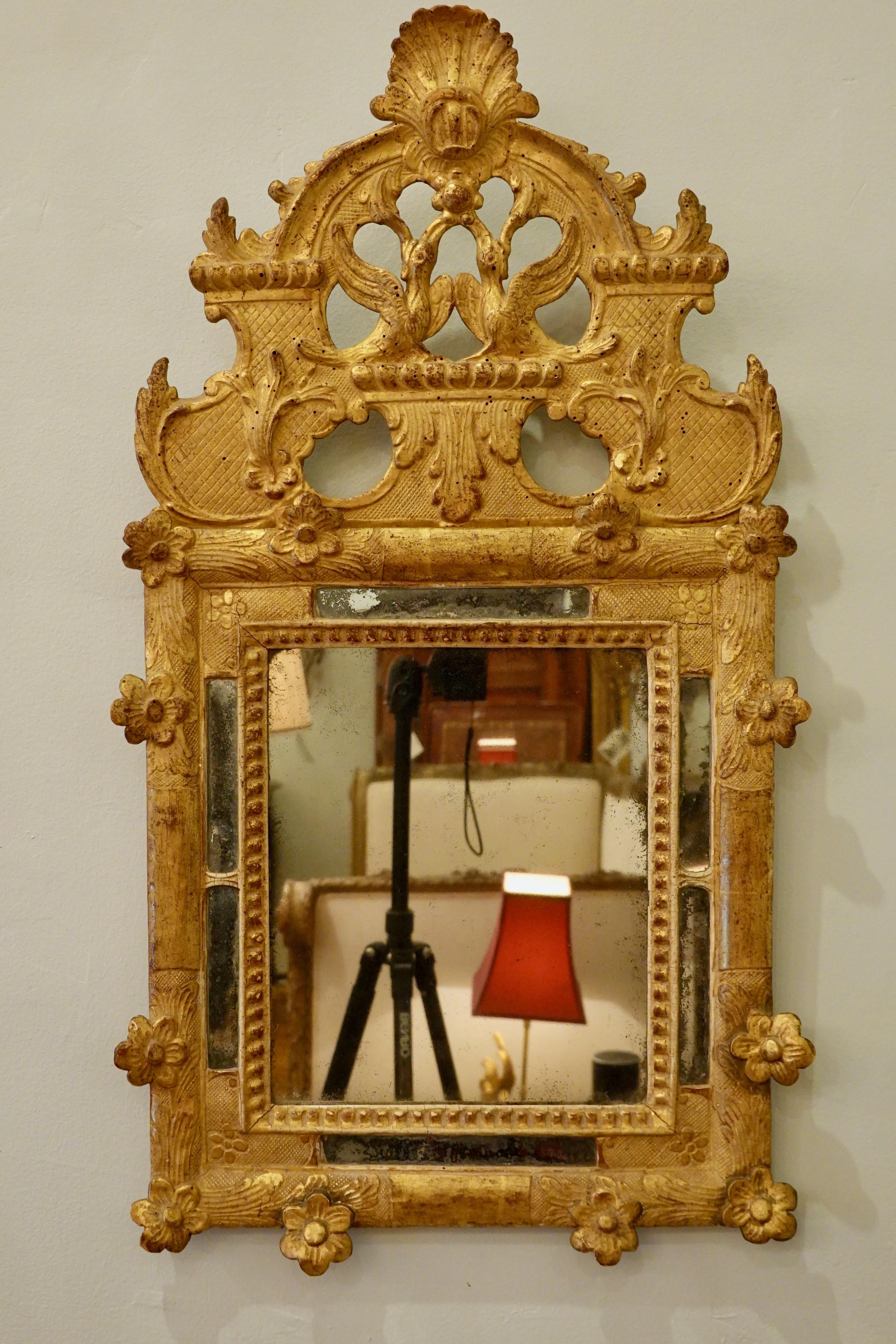 French Regence period giltwood parclose mirror (18th century), with beautifully-detailed carved birds and scallop shell on pediment, and flowers and other decoration around the frame. Very nice example of mercury glass, which appears original. The