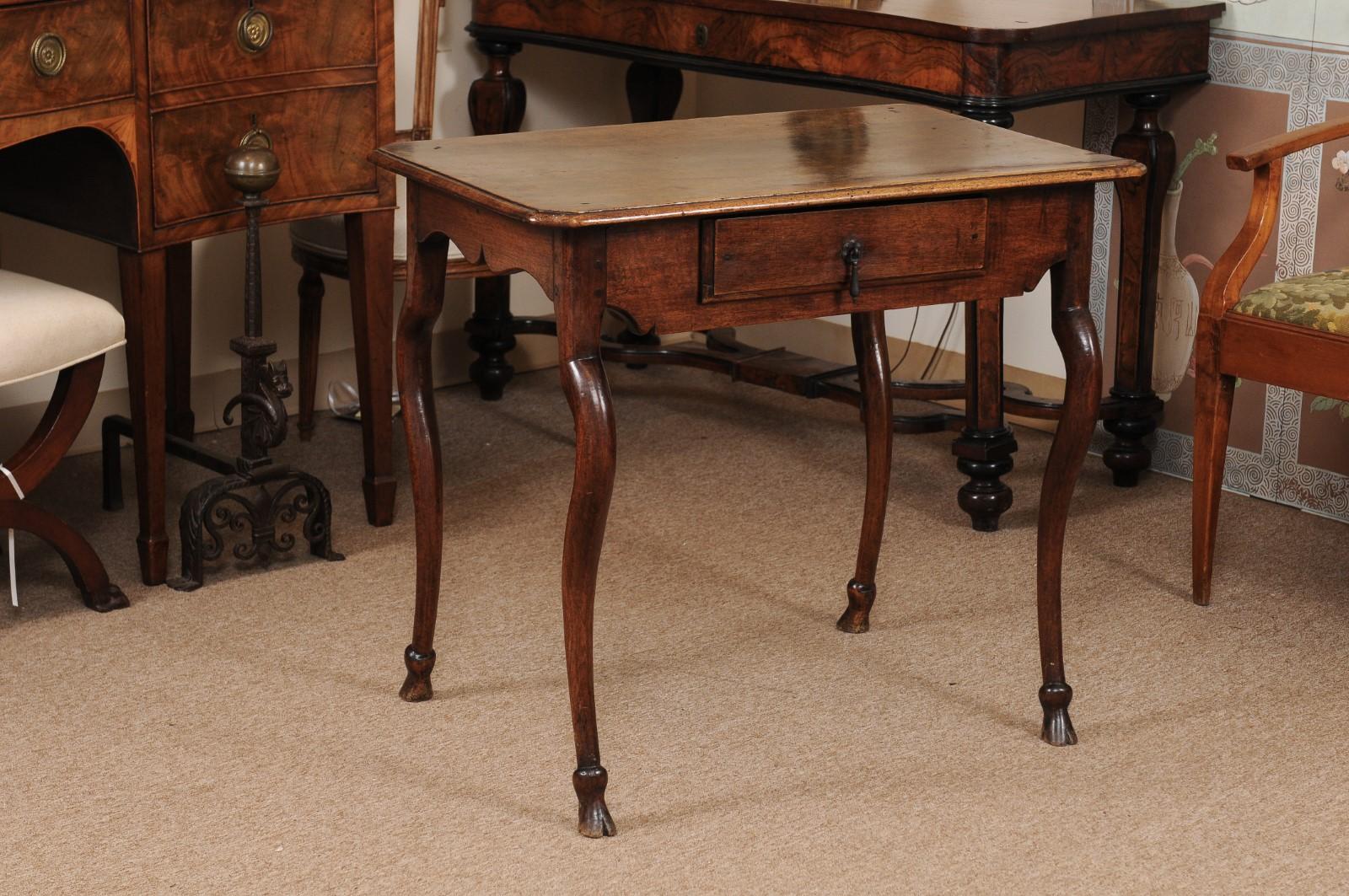 A French Regence walnut table with rectangular top with molded edge, drawer below in apron and unusual cabriole legs ending in carved hoofed feet. The table finished on all sides.