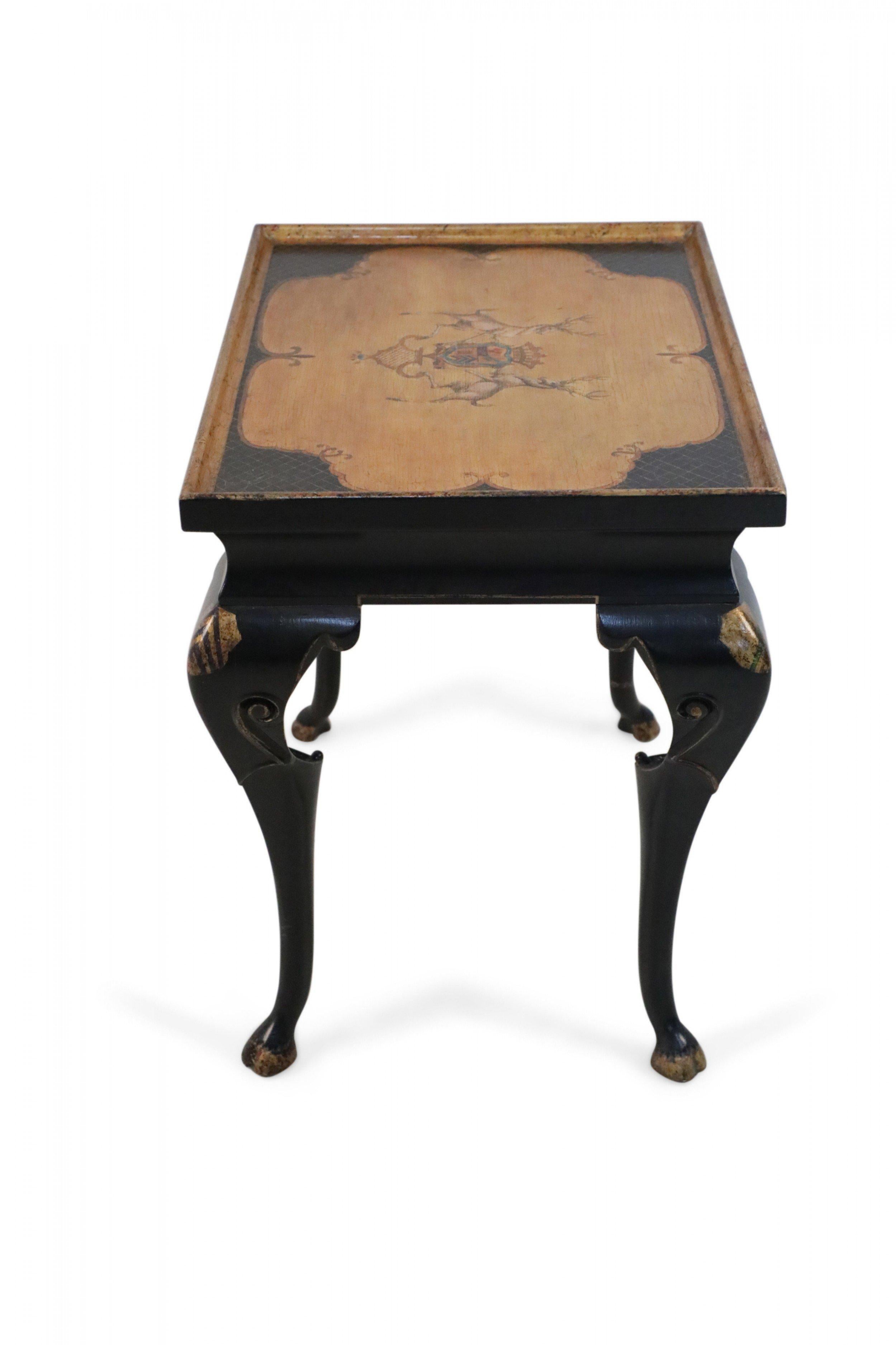 French Regence-style (modern) black end table with cabriole legs and an apron decorated in gold accents, supporting a top with golden lattice patterns on a black ground surrounding a bare wooden medallion painted with two deer flanking a coat of