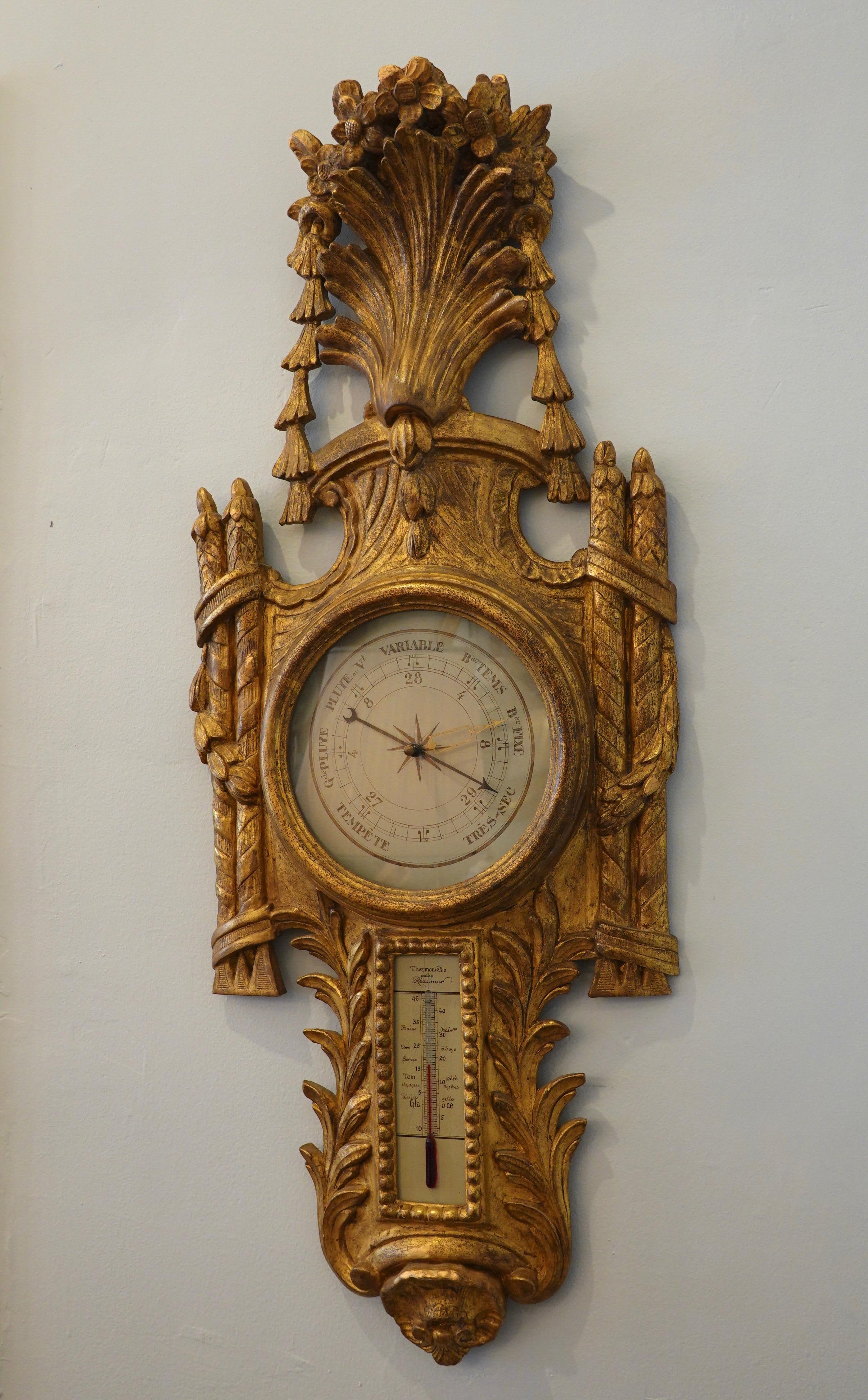 French Regence style giltwood barometer and thermometer, surmounted with an acanthus leaf cartouche draped with flowers and swags, the dial is flanked with pillar and ribbon carvings, and a scallop shell with laurel leaves ornaments the bottom. The