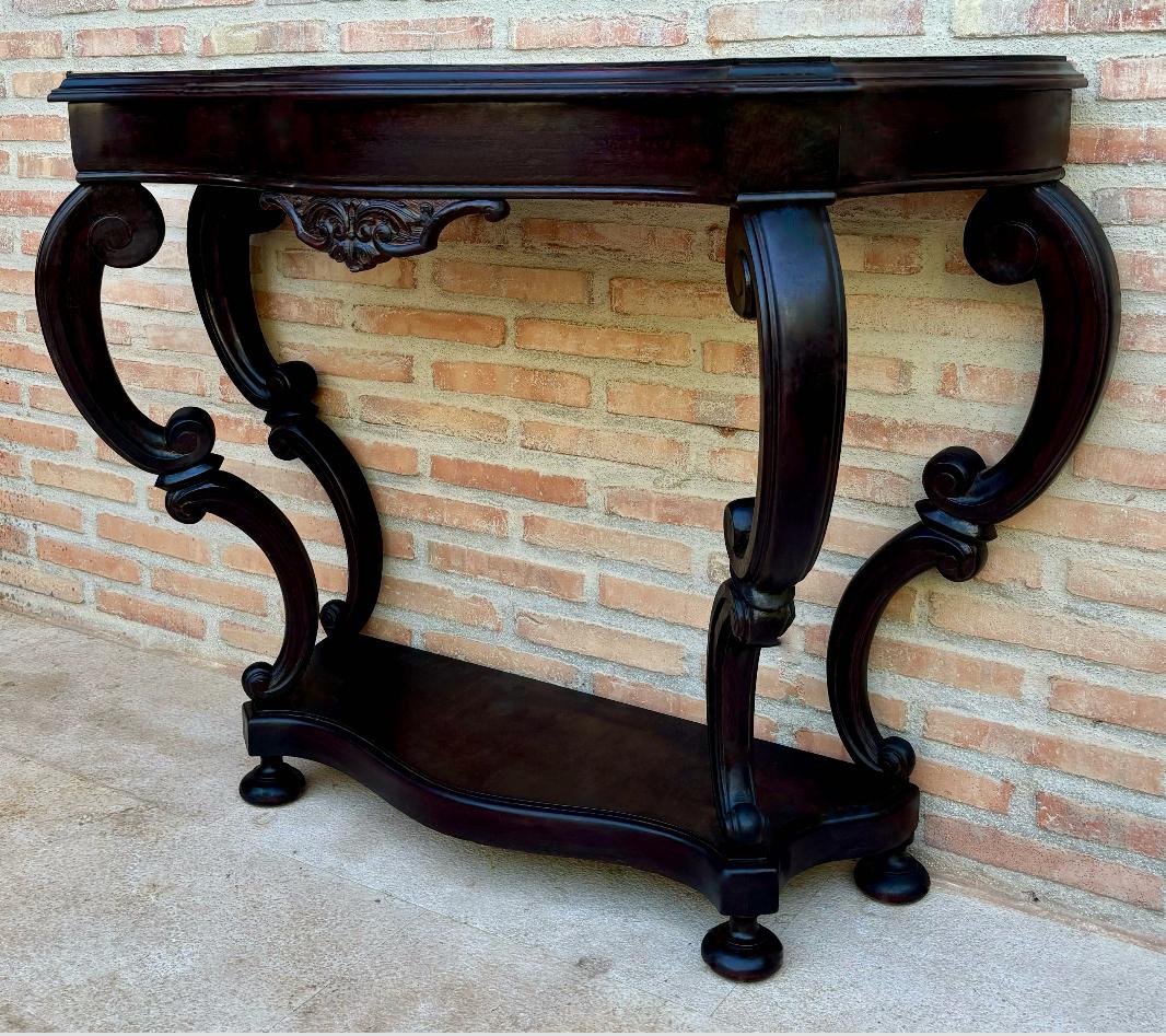 Consolle in stile Regency in legno massiccio, realizzata a mano con pregiati legni duri.
Si tratta di un tavolino antico risalente al 1850 circa. In tonalità scura con una bella patina invecchiata, il piano mostra un buon dettaglio delle venature ed