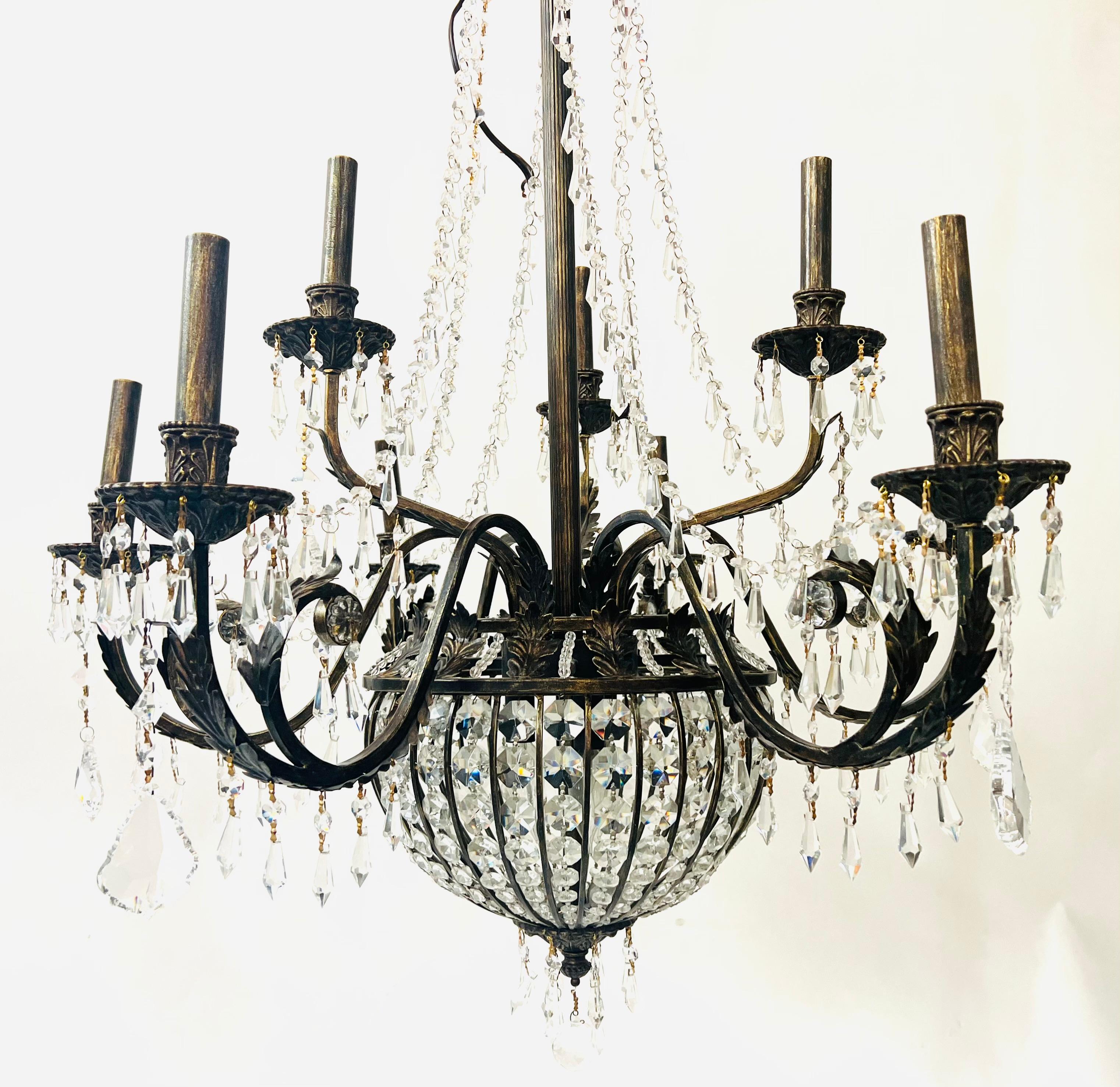 An early 20th century French Regency Empire bronze and cut-crystal basket chandelier. Featuring 9 large arms ending with French style bobeche in bronze embellished with crystals and large facetted drops. Crystal swags adding style to this refined