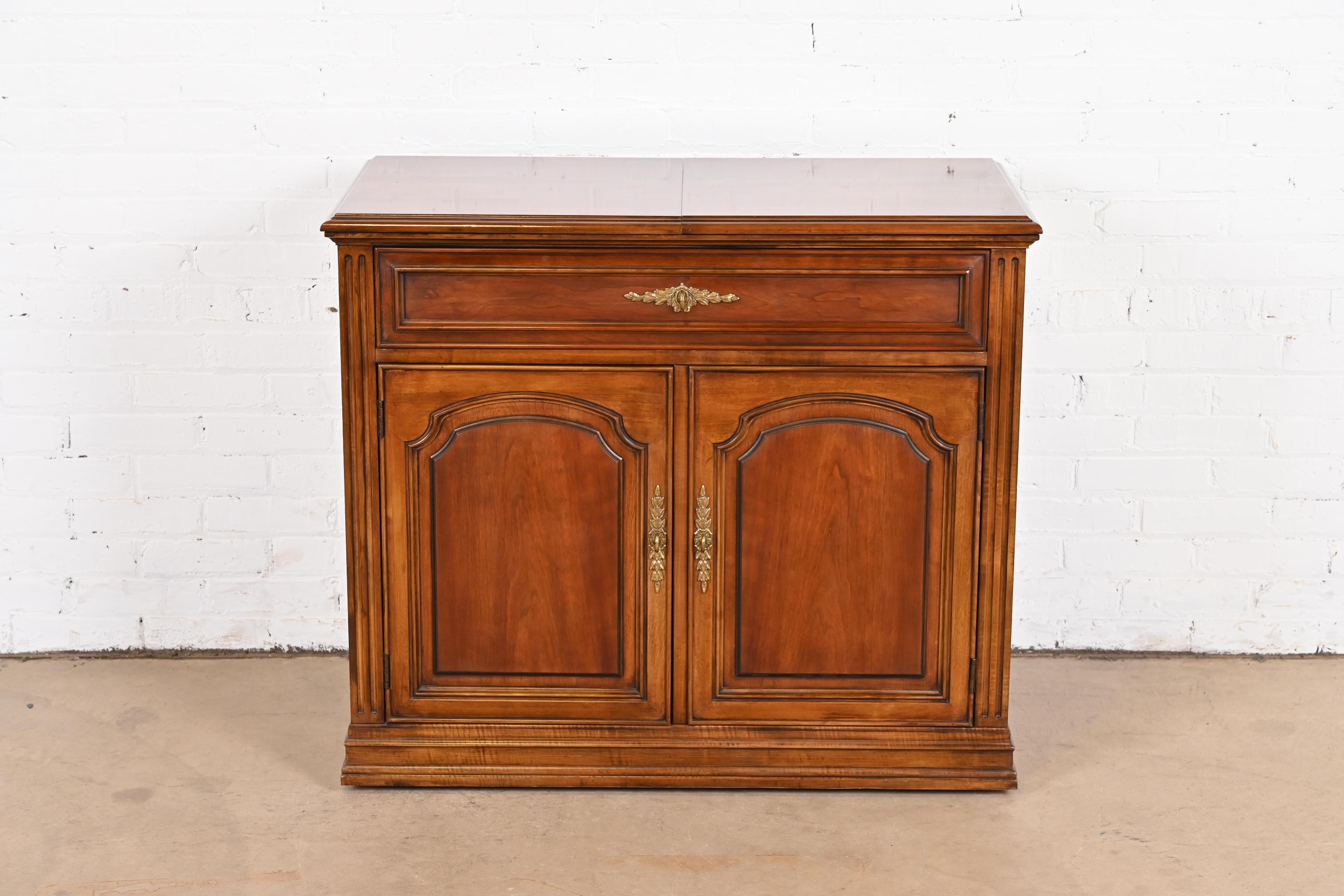 A beautiful French Regency Louis XVI style flip top rolling buffet server or bar cabinet

By White Furniture

USA, circa 1970s

Carved cherry wood, with original brass hardware.

Measures: 38