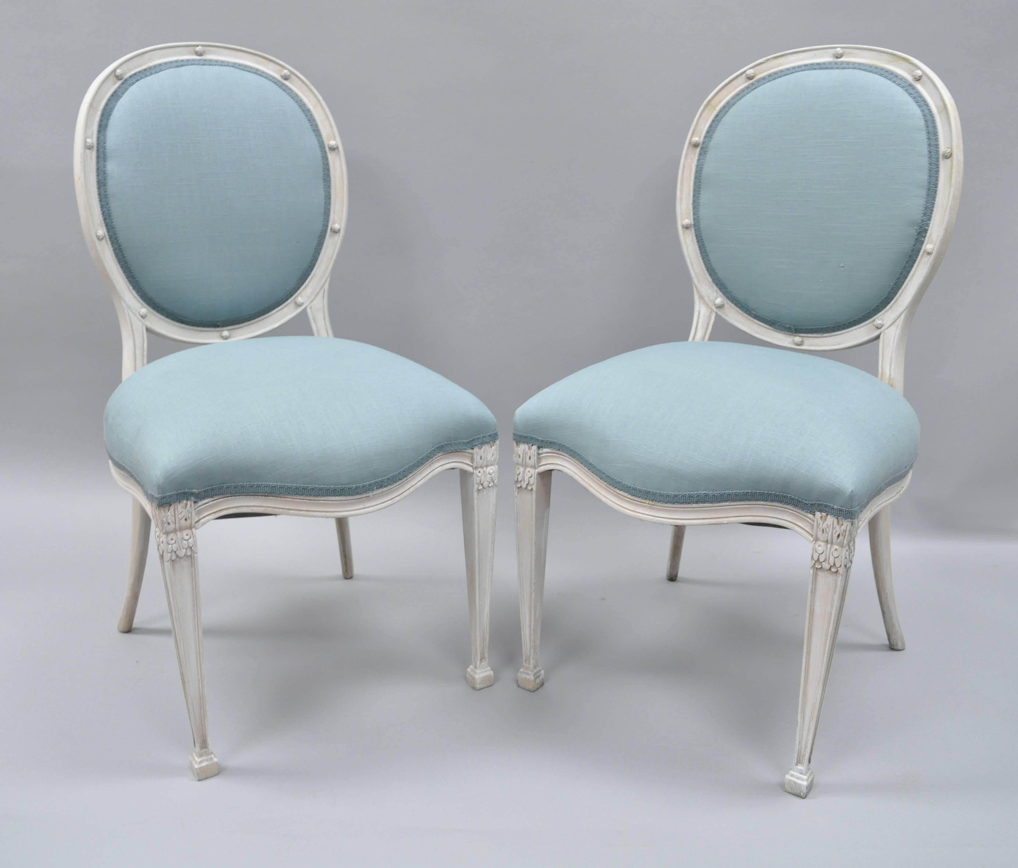 Set of six French Regency or neoclassical style dining side chairs, circa late 20th century. Set features solid wood construction, white distress painted finish, oval upholstered backs, blue fabric, sleek tapered legs, nice carved details.