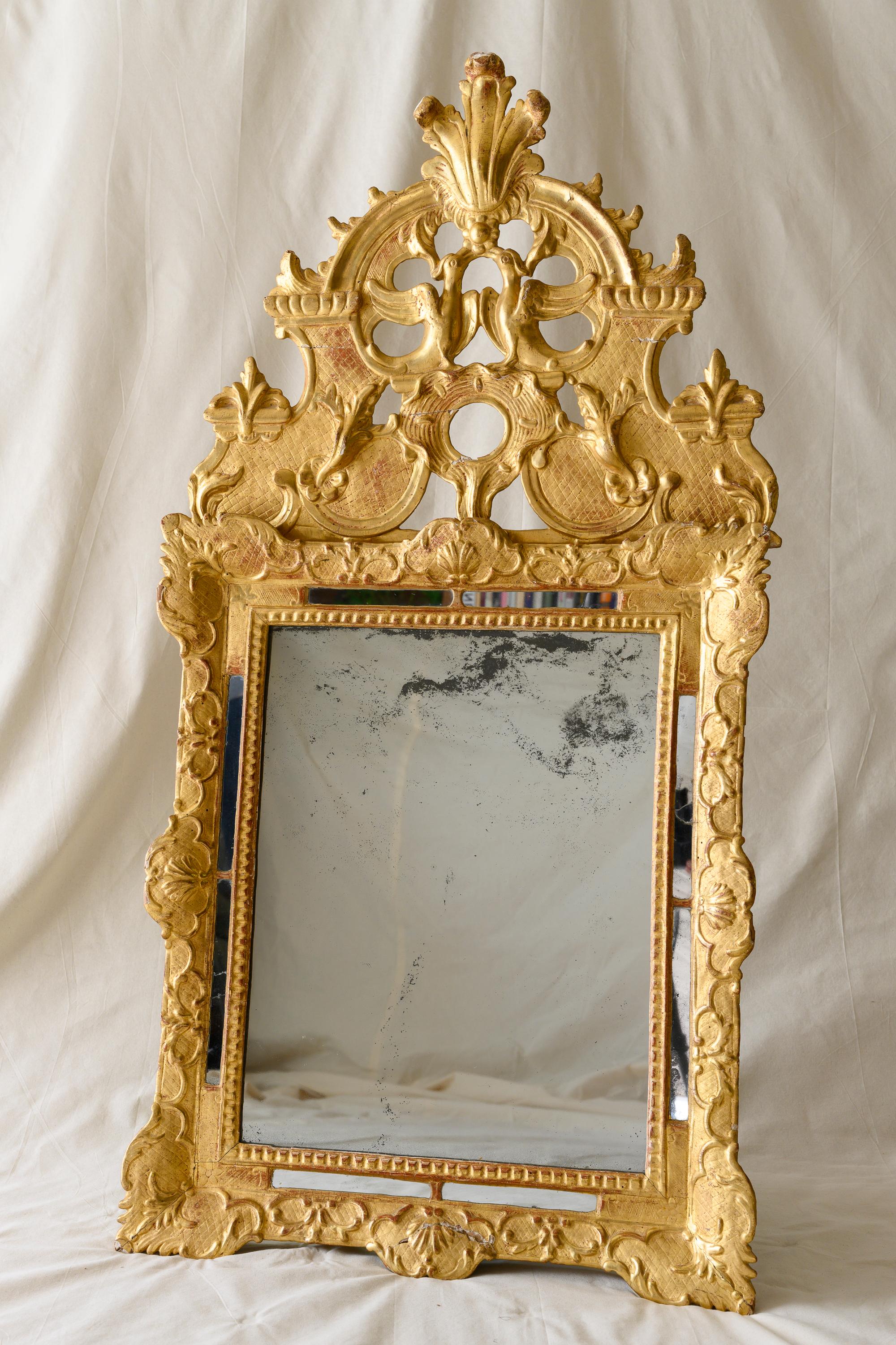 Miroir de mariage en bois doré de la période Régence, présentant une plaque rectangulaire en verre au mercure avec une bordure de perles et de miroirs, un cadre sculpté de feuillage et de festons surmonté d'une crête sculpturale centrée de deux