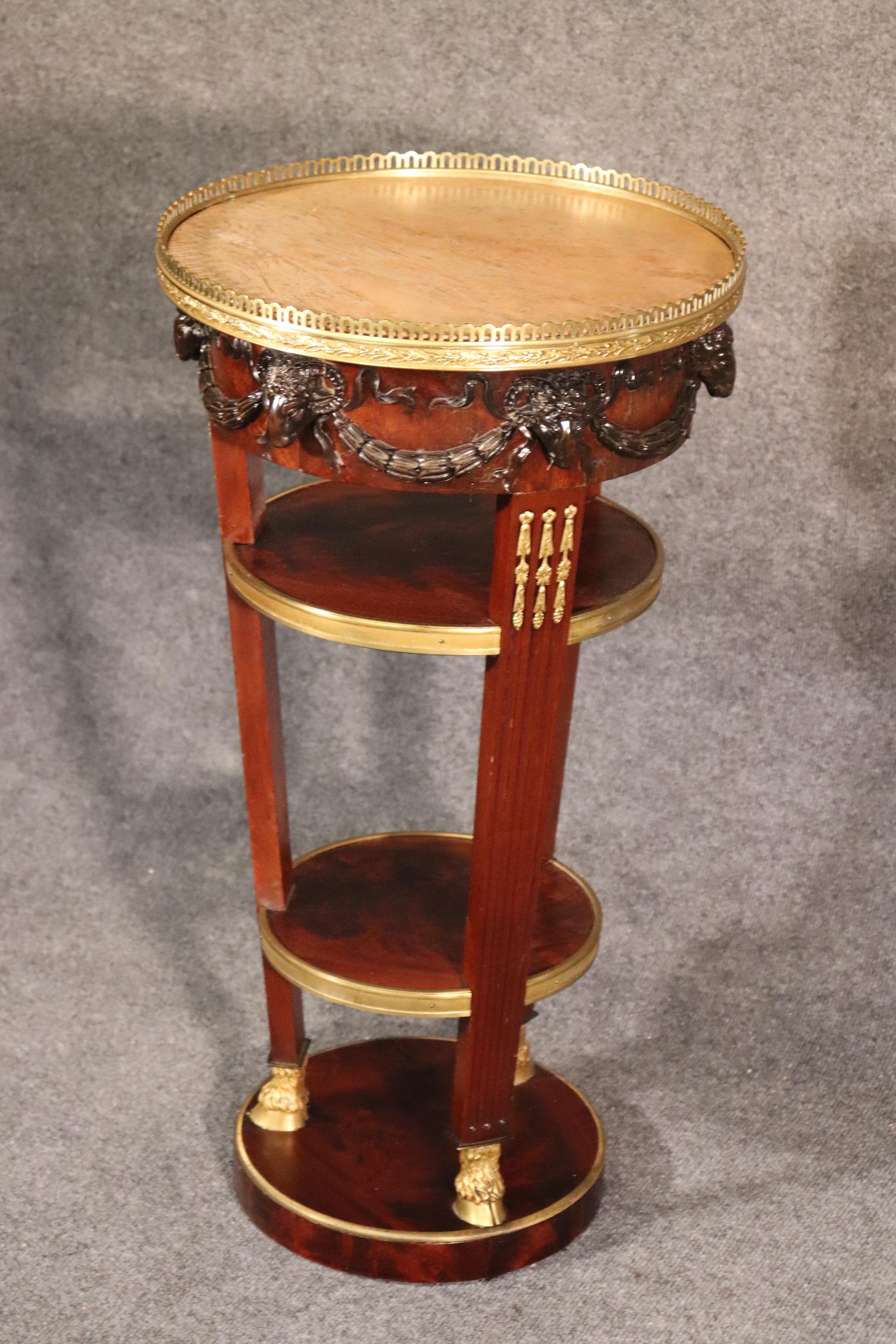 This is a stunning end table made of solid walnut and featuring a gorgeous slab of round marble on top with a complimenting brass gallery and carved ram’s heads on the terminals at the top. The stand has been French-polished and is in superb