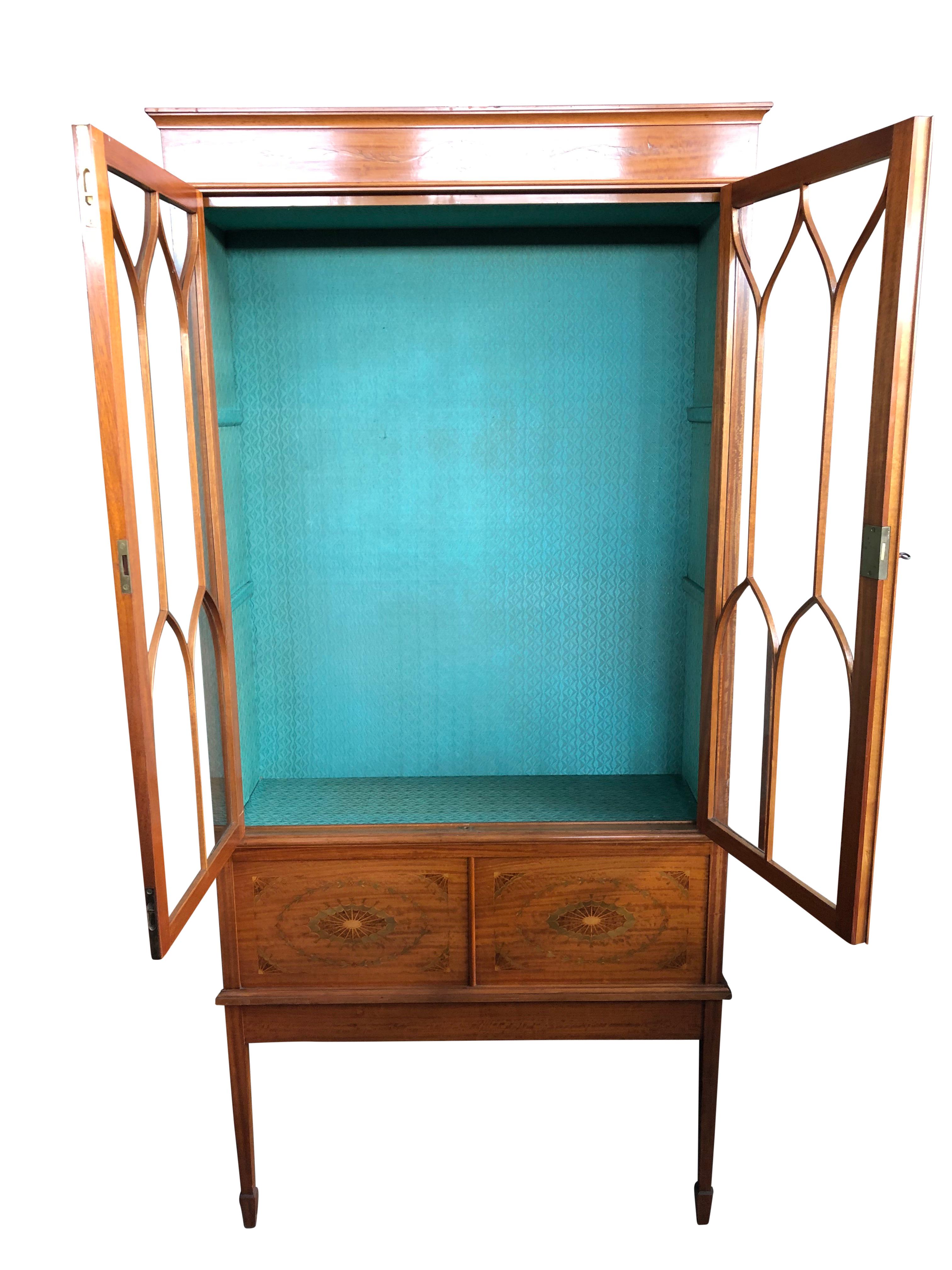 A superb French Regency style Sheraton lit and glass cabinet with a beautiful pine green rear. The cabinet features two drawers with stunning marquetry inlay.