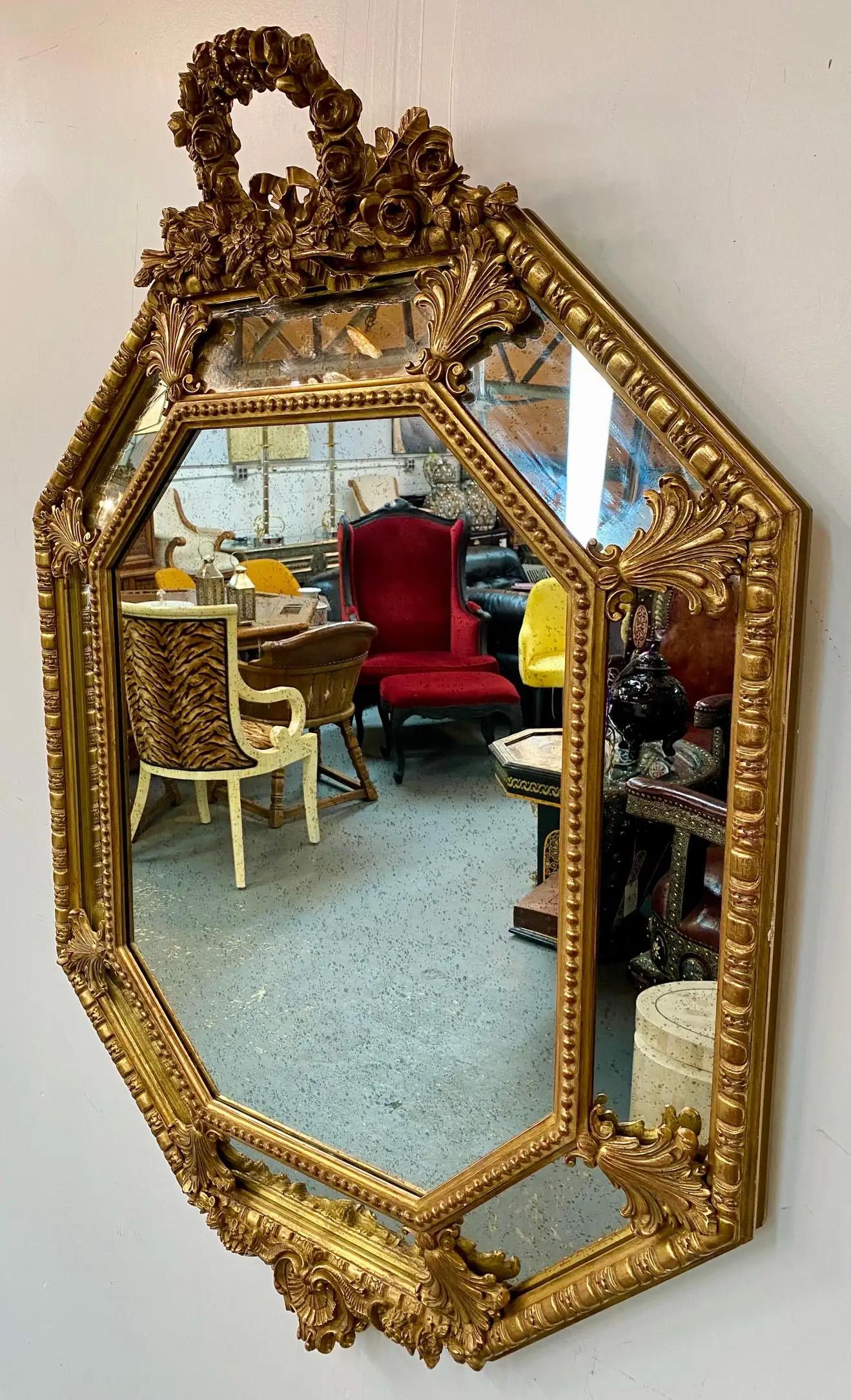 Ein exquisiter Spiegel aus vergoldetem Holz im französischen Regency-Stil. Der Spiegel aus dem späten 19. Jahrhundert hat eine achteckige Form und ist sehr fein gearbeitet. Das Wappen ist aufwendig geschnitzt und zeigt ein florales Muster und eine
