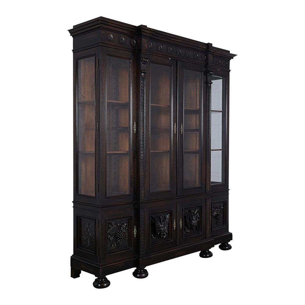This ebonized French 19th-century renaissance style bookcase has been professionally restored, has hand-carved details throughout the piece, and is newly waxed giving it a beautiful patina finish. The piece has unique carvings on the top crown with