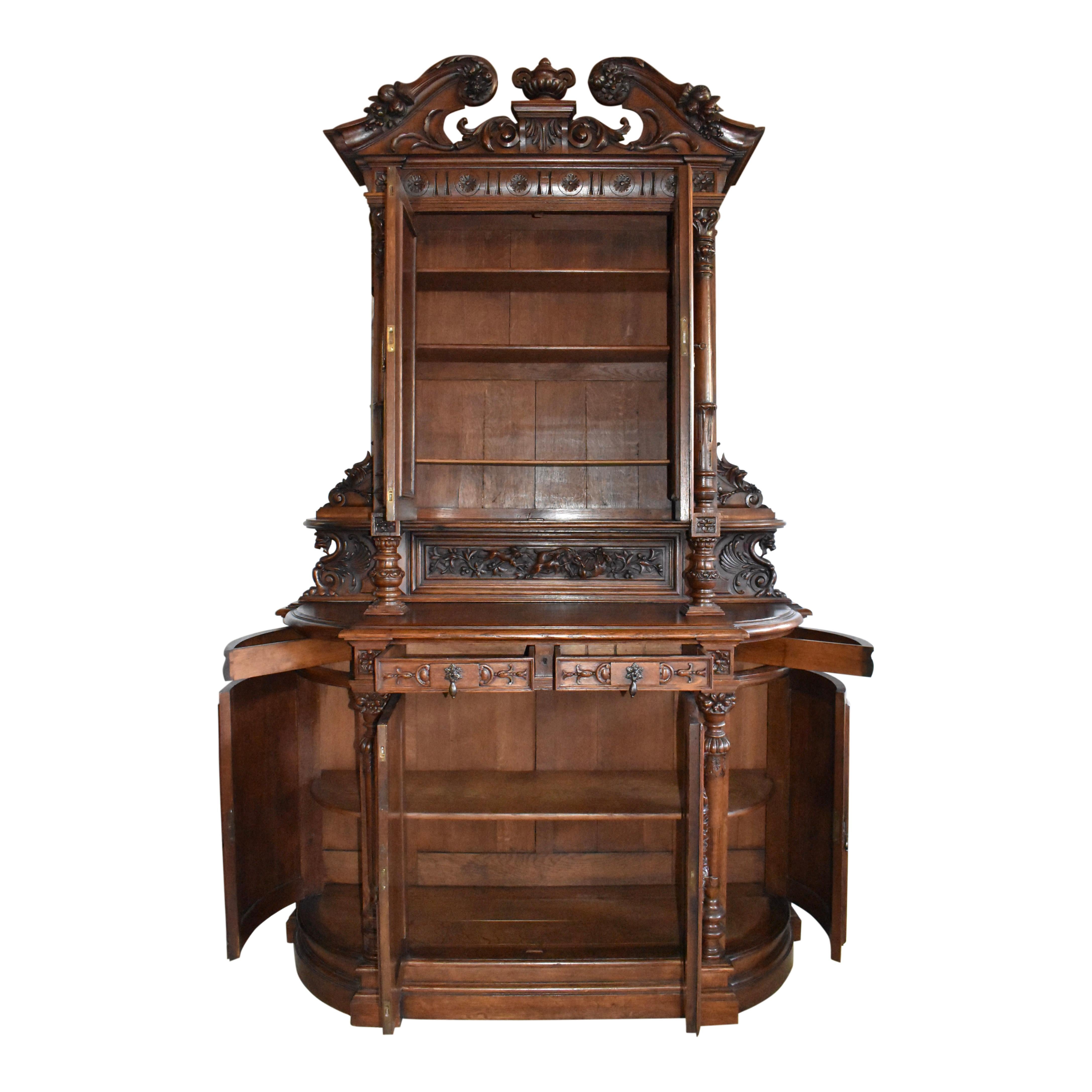 Fine craftsmanship and lavish carvings abound in this handsome Renaissance Revival Hunt cabinet, which was created in France in the late-19th century from European oak. The cabinet is two pieces with the top raised on carved pillars and a carved