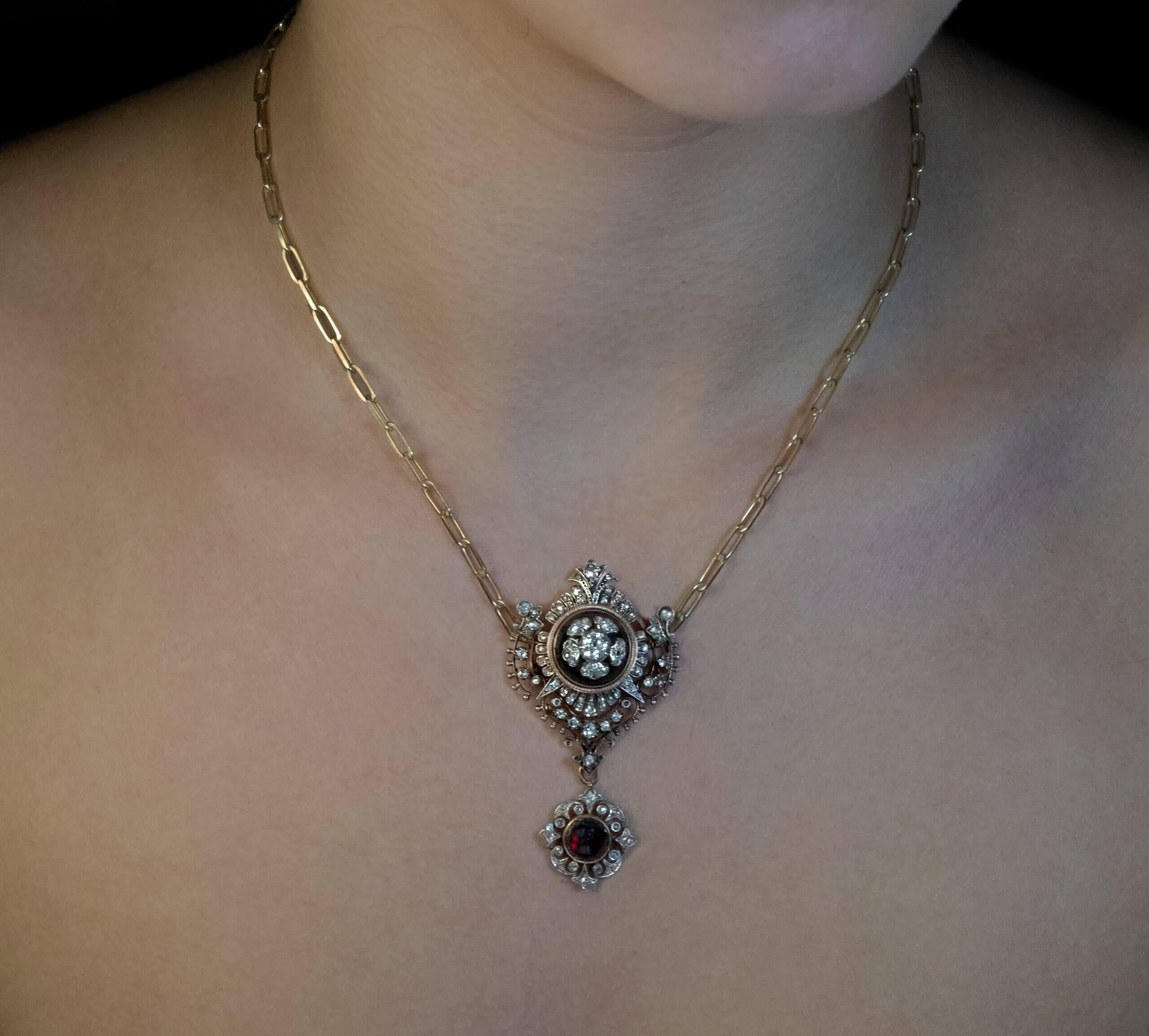 Francia, circa 1860  Questo antico ciondolo/spilla in oro e argento 18 carati è disegnato nello stile rinascimentale del 1500. Presenta due granati rossi profondi tagliati a cabochon, incorniciati da castoni traforati e impreziositi da numerosi