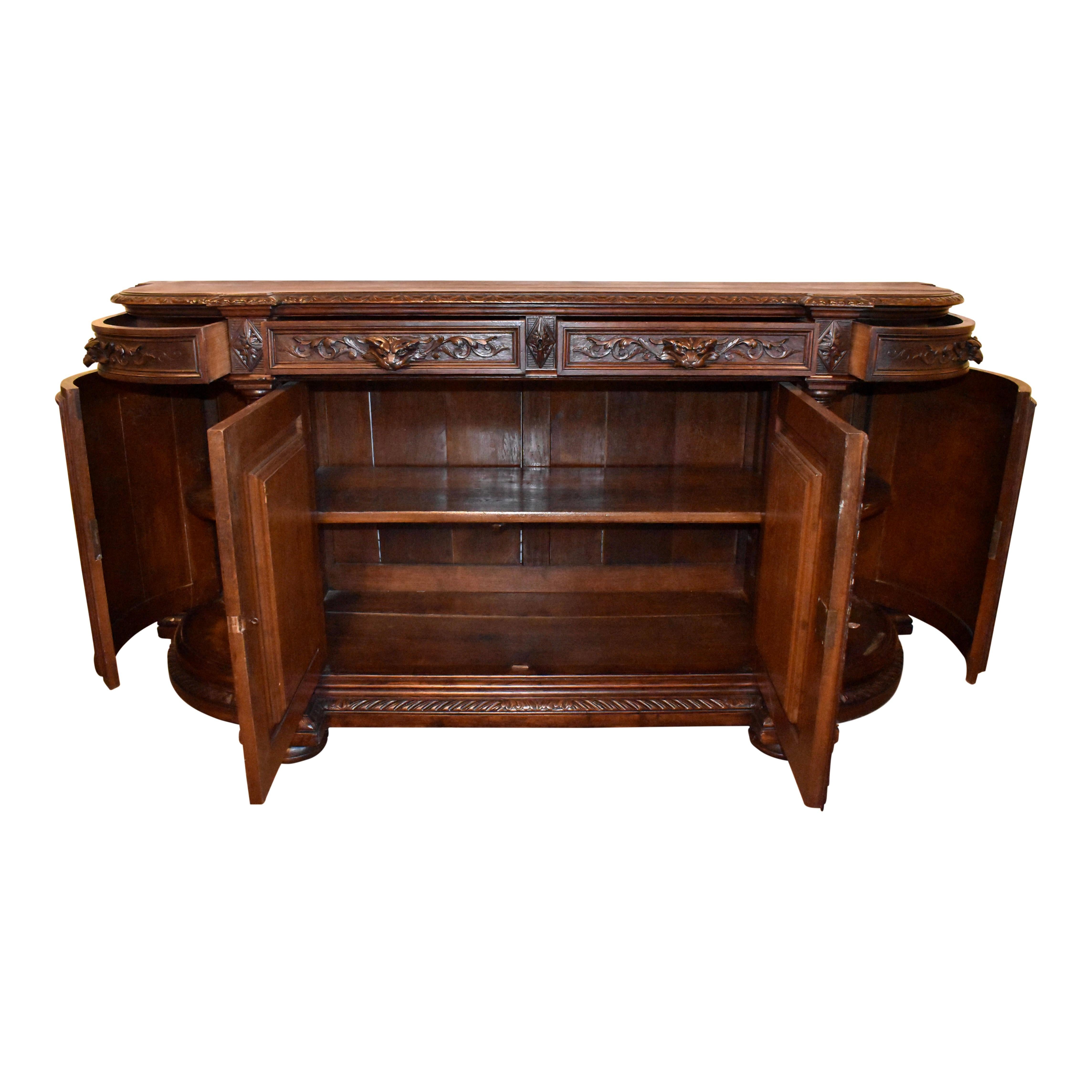 Fine craftsmanship and lavish carvings abound in this handsome Renaissance Revival sideboard, which was created in France in the late-19th century from European oak and finished with a rich, dark stain. Bowed at the sides, the sideboard's top is