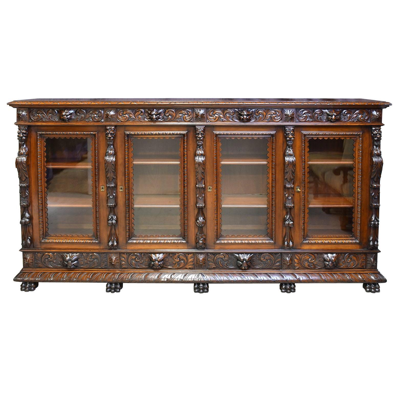 An exquisite bookcase or vitrine in the style of Henri II (Renaissance) in a very fine quality French walnut with well-articulated carvings in high relief of acanthus foliage & rosettes, intermingled with carvings of grotesques in the arabesques, in