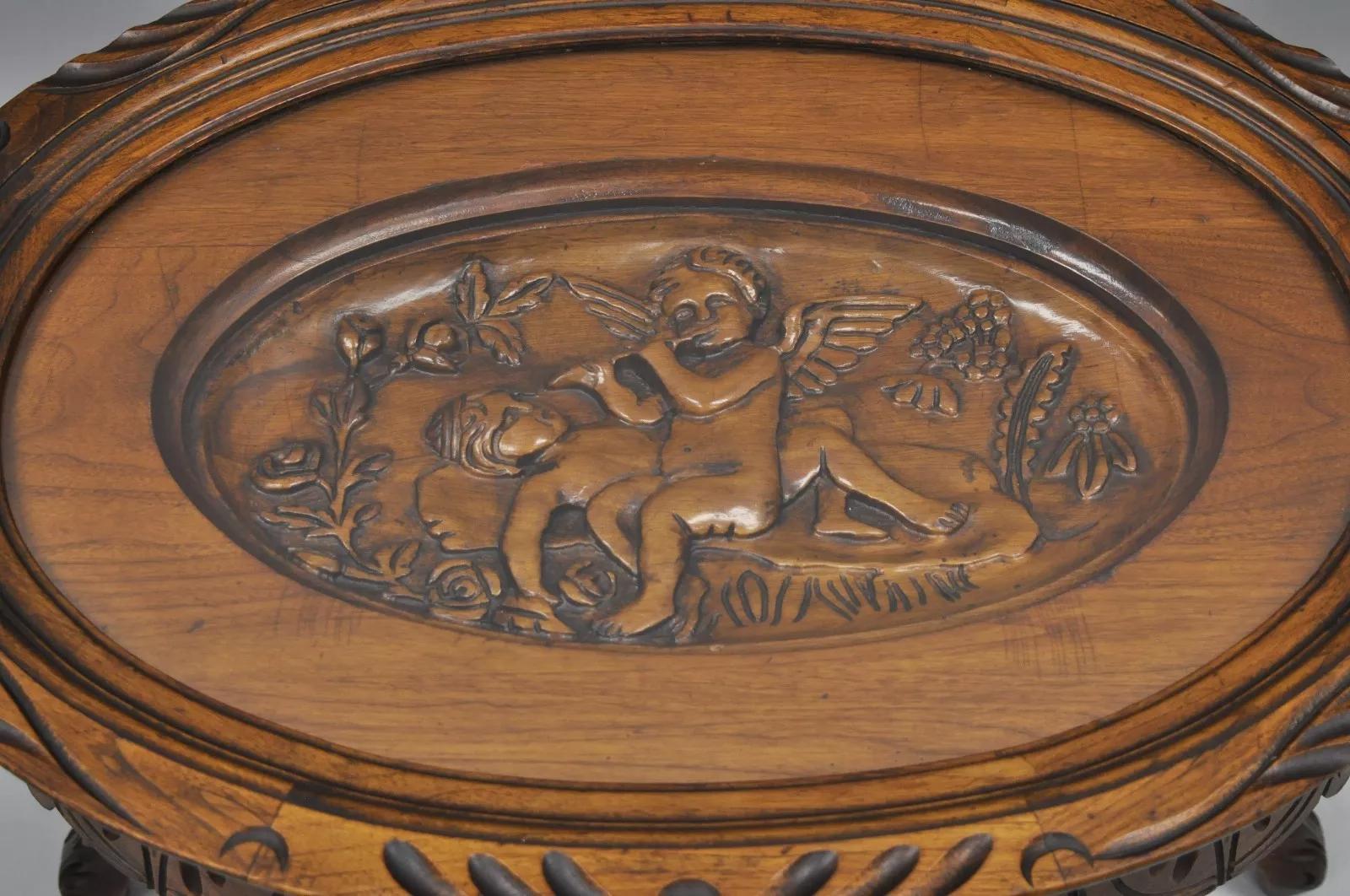 Antique French Renaissance Style Mesa de centro con bandeja de nogal y tapa de cristal con querubines tallados . El artículo presenta una bandeja superior de cristal extraíble, una escena de querubín tallada, construcción de madera maciza, detalles