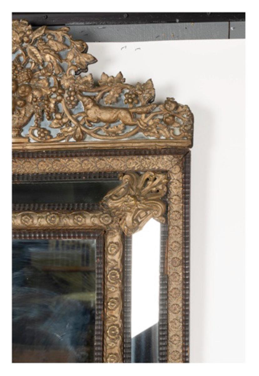 Dies ist ein Beispiel für einen sehr guten französischen Repousse-Spiegel mit erhabenen, abgeschrägten Glaseinsätzen, die den Repousse-Rahmen umgeben. Das repoussierte Wappen zeigt ein Hundepaar vor einem Blumenwappen. Der Spiegel ist in einem