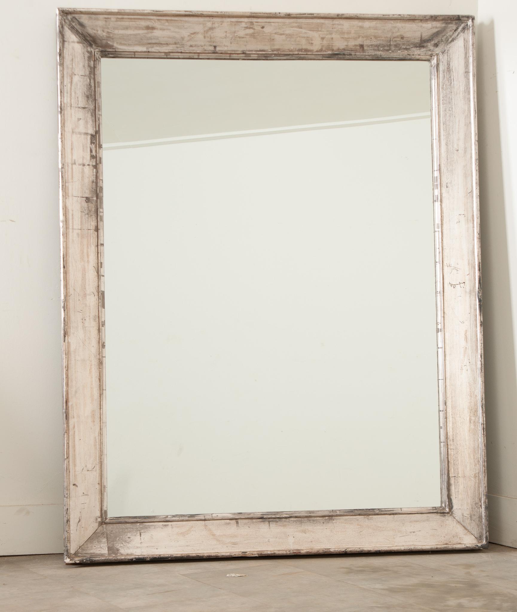 A recently made, substantial, beveled wood mirror frame has an intentionally worn silver gilt finish. New mirror plate. This mirror is sure to make a statement in any interior. Be sure to view the detailed images. 