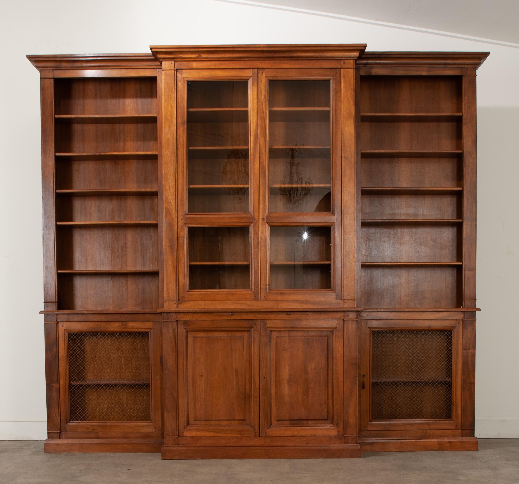 This classically designed breakfront bibliotheque was custom made with beautiful walnut veneer. The center of the bookcase has two glass paneled doors with five adjustable shelves measuring 12.5” deep, below are two pull out slides measuring 33 ½”
