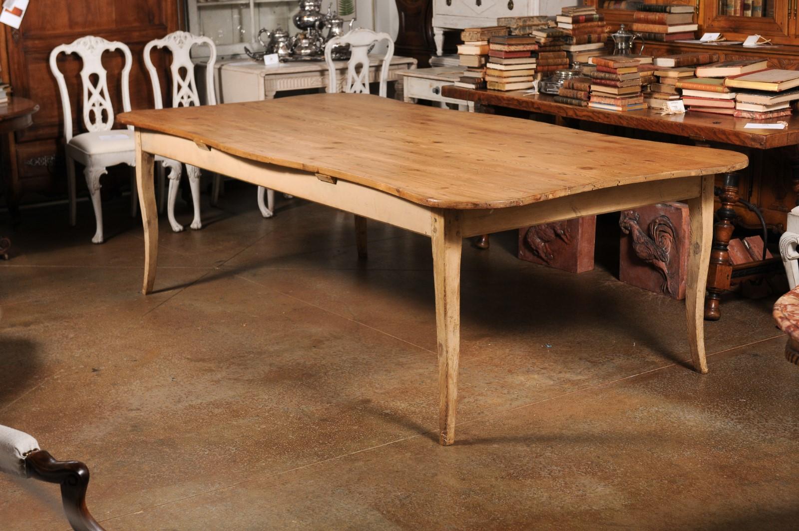 A French Restauration period fir wood farm dining room table from the early 19th century, with planked top, serpentine accents, curving legs and distressed patina. Created in France during the Restauration period which saw a return of the Bourbon