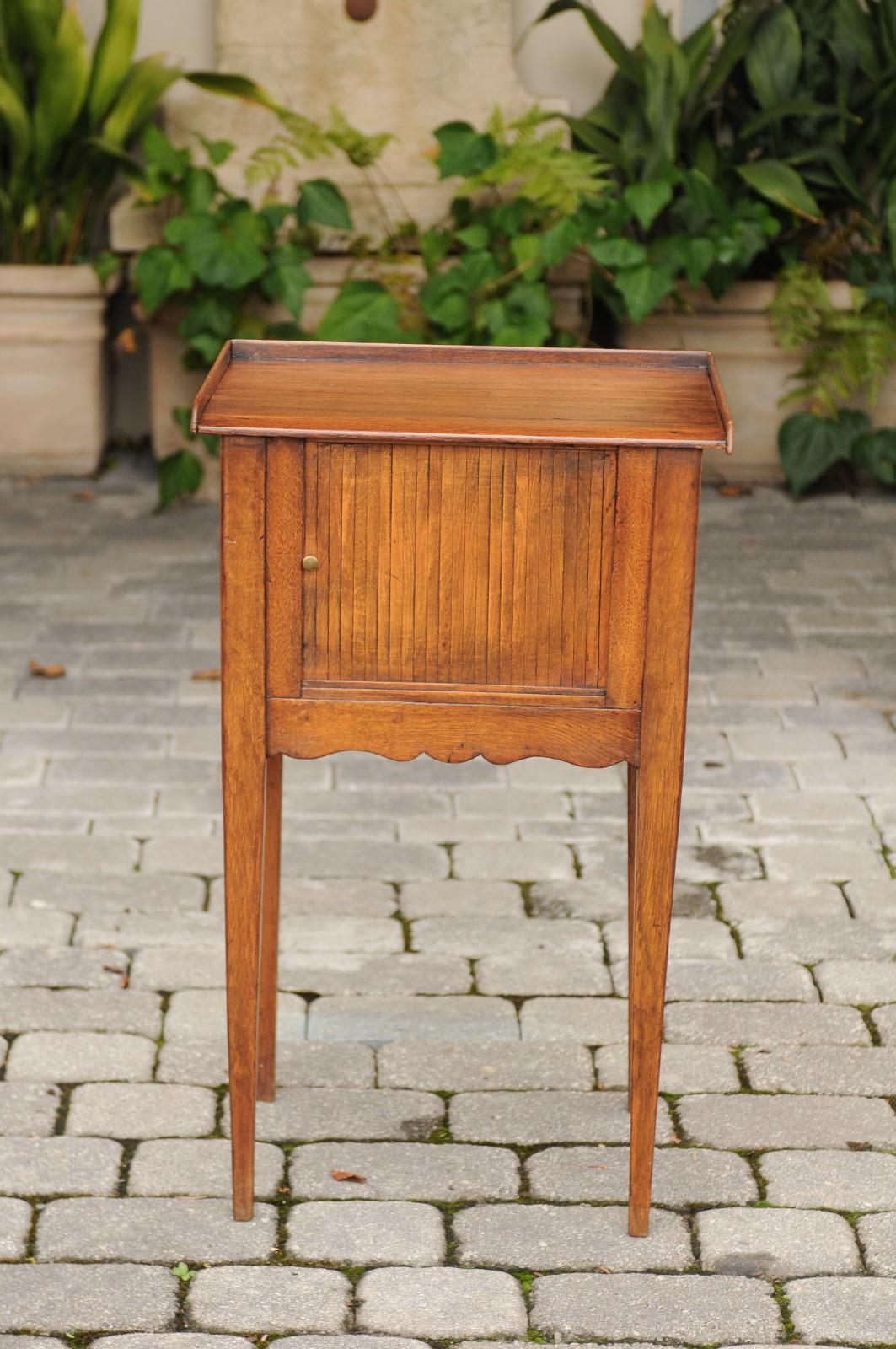 A petite French Restauration period oak bedside table from the early 19th century, with tambour door, tray top and tapered legs. Born during the French Restauration period that saw the return of monarchy after the first French revolution, this