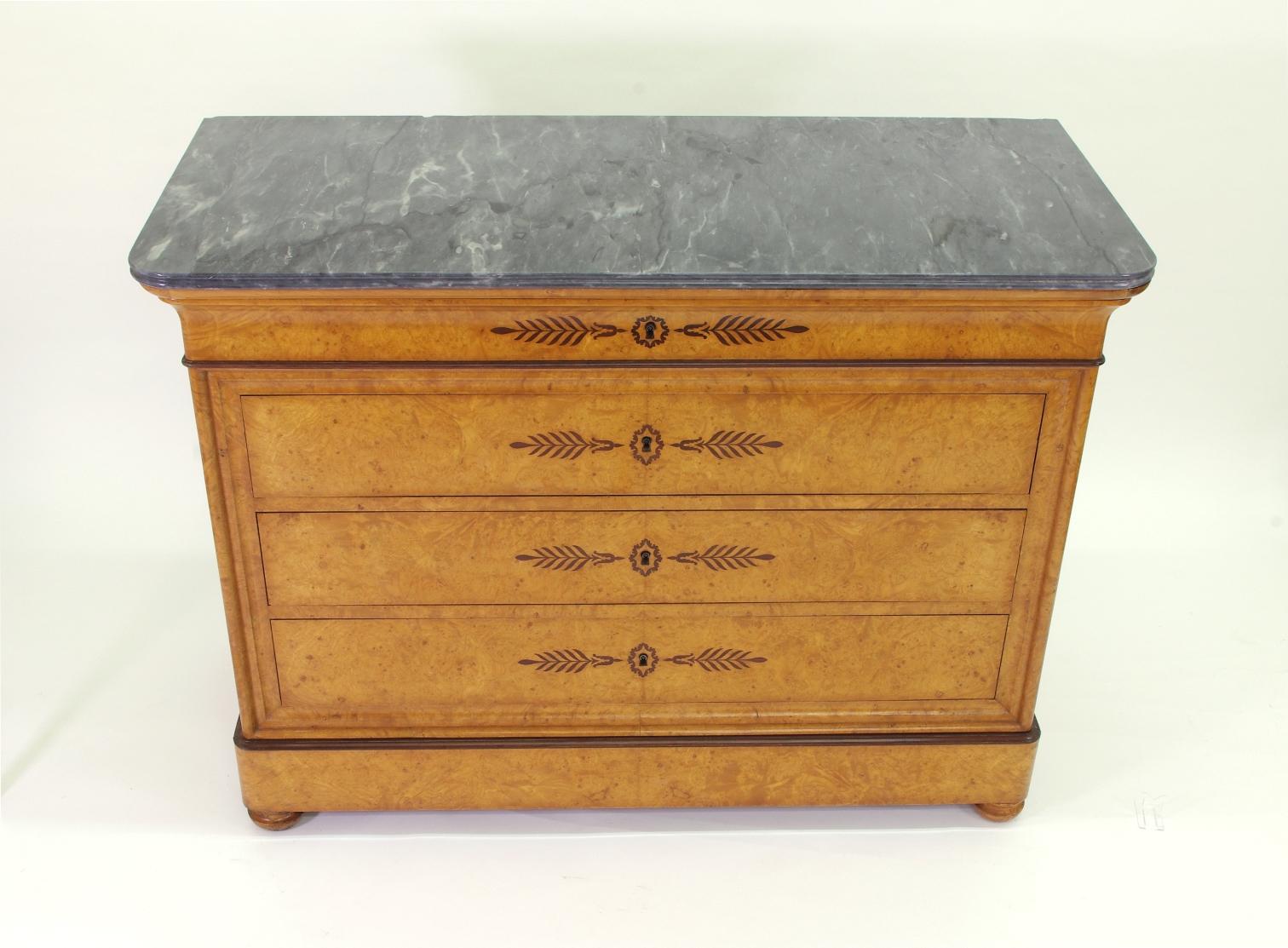 French restauration (Charles X) burl ash chest of drawers, the gray marble-top (Blue Turquin) over four long drawers, each with purple-heart inlay and a fine locking mechanism; the turned bun feet joined by a secret drawer.

This beautiful chest
