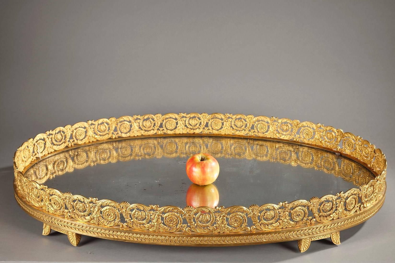 Sizable restauration centerpiece in ormolu on four scrolling feet of foliage. The oval base is covered with a mirror that is surrounded by an open work frieze. The frieze is delicately sculpted with foliated rinceau, flowers, seeds and wheat and it