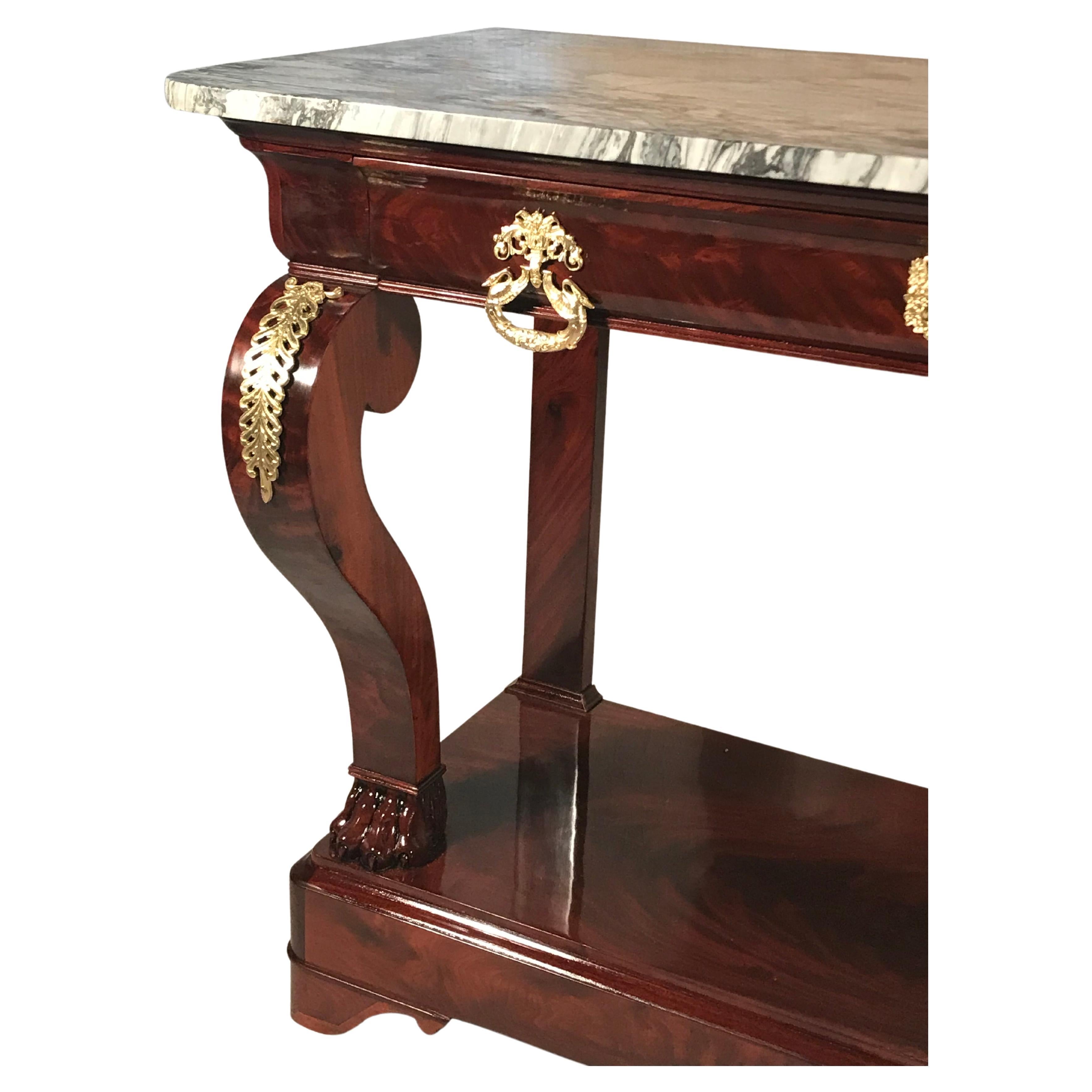 This beautiful French Restoration Console table dates back to around 1830. The console table has a pretty mahogany veneer. The s-shaped front legs which Stand on lion claw feet are decorated with bronze fittings. The console table has one central