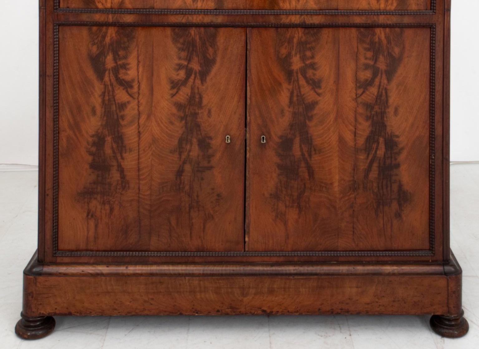 French Restauration mahogany drop-front secretary or secretaire a abbatant, with molded rounded rectangular cornice above a frieze drawer, drop-front desk and pair of cabinet doors, all veneered in bookmatched flame mahogany, the drop front opening