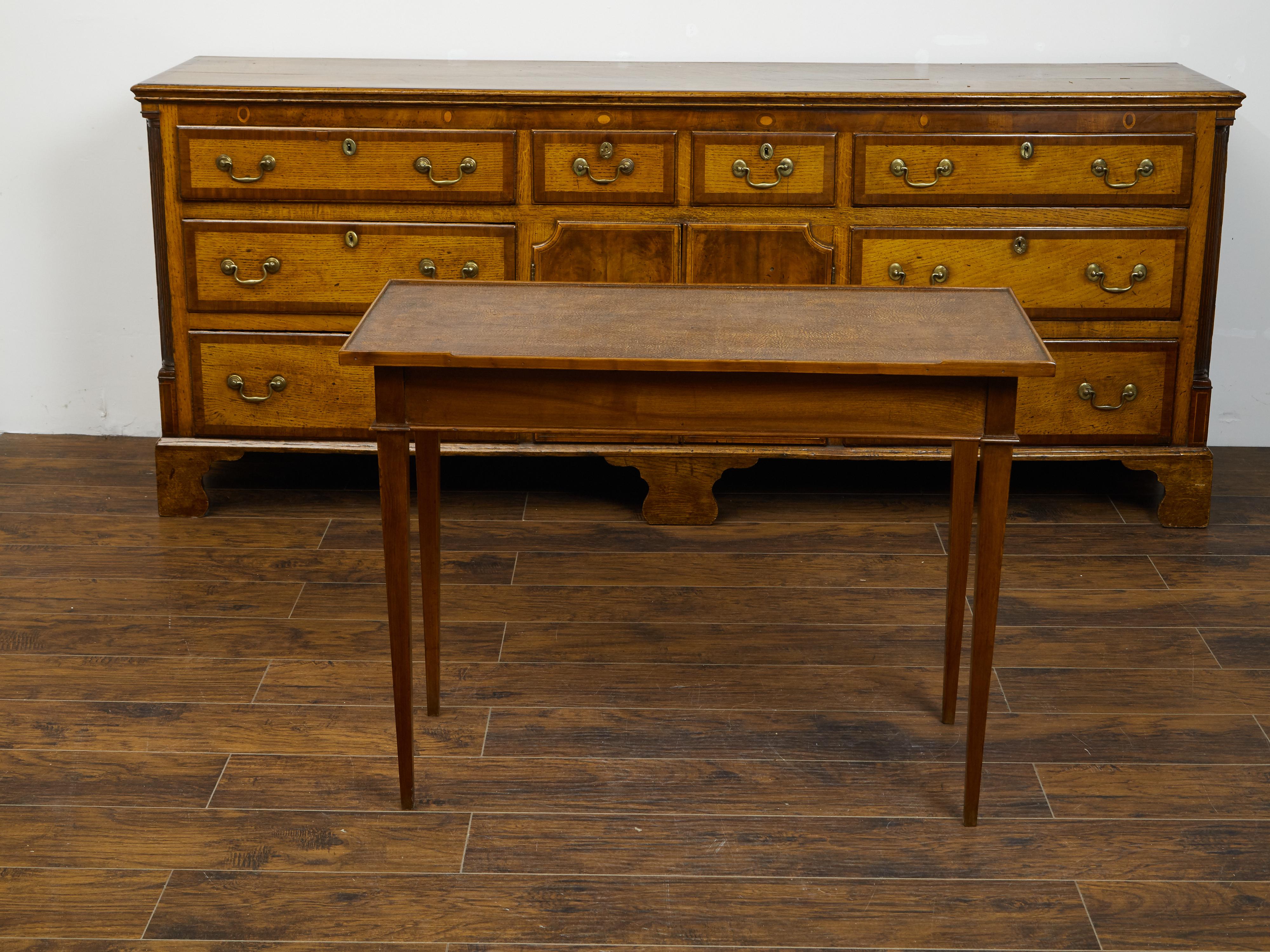 A French Restauration period wooden side table from the early 19th century, with leather top, lateral drawer and tapered legs. Created in France during the Restauration period, this side table features a rectangular leather top sitting above an