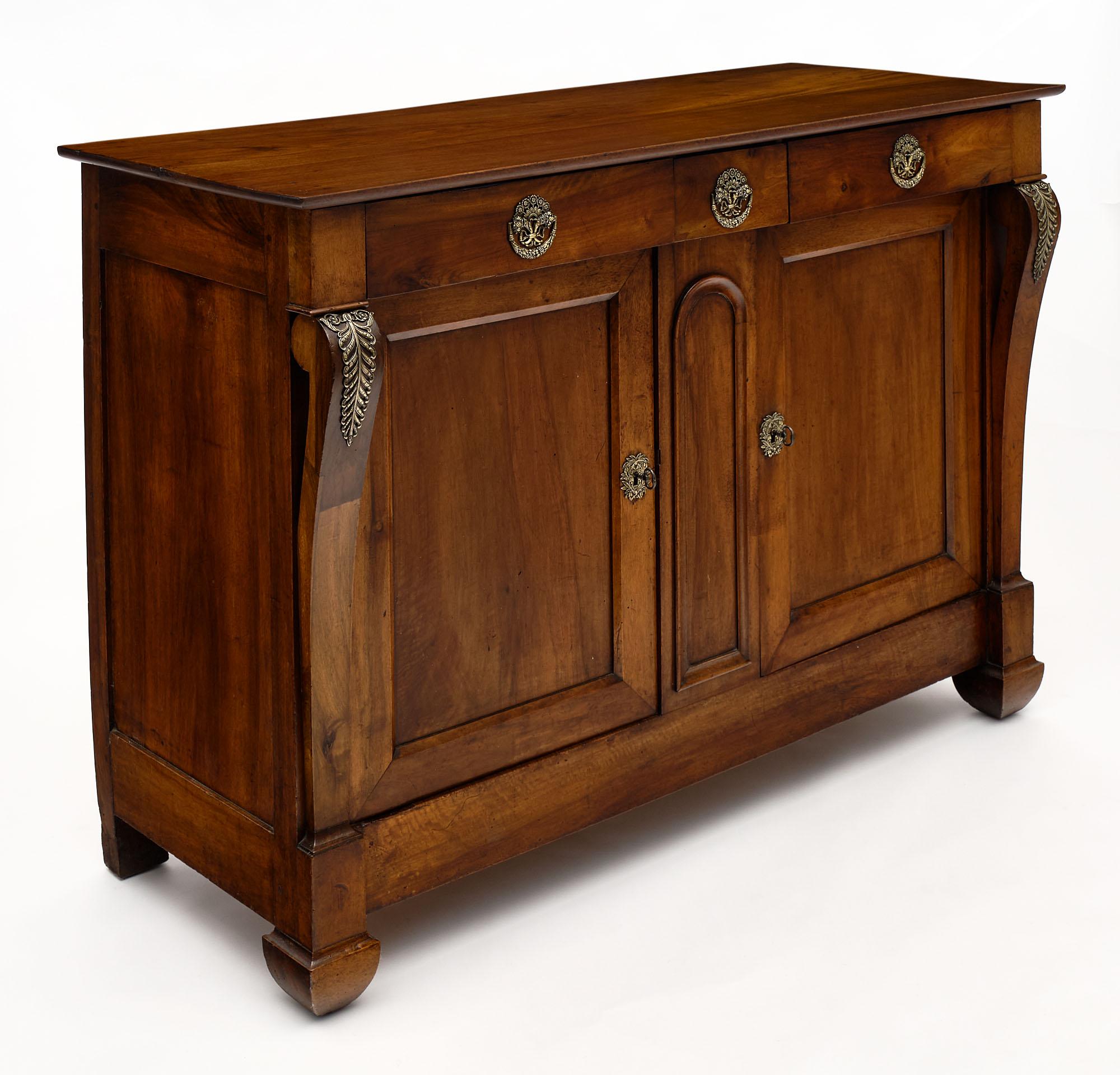 Buffet / credenza from France made of solid hand-carved walnut. It features carved “consoles” on the sides; two dovetailed drawers; and doors that open to interior shelving. There are richly cast period bronzes throughout and a working lock and key.