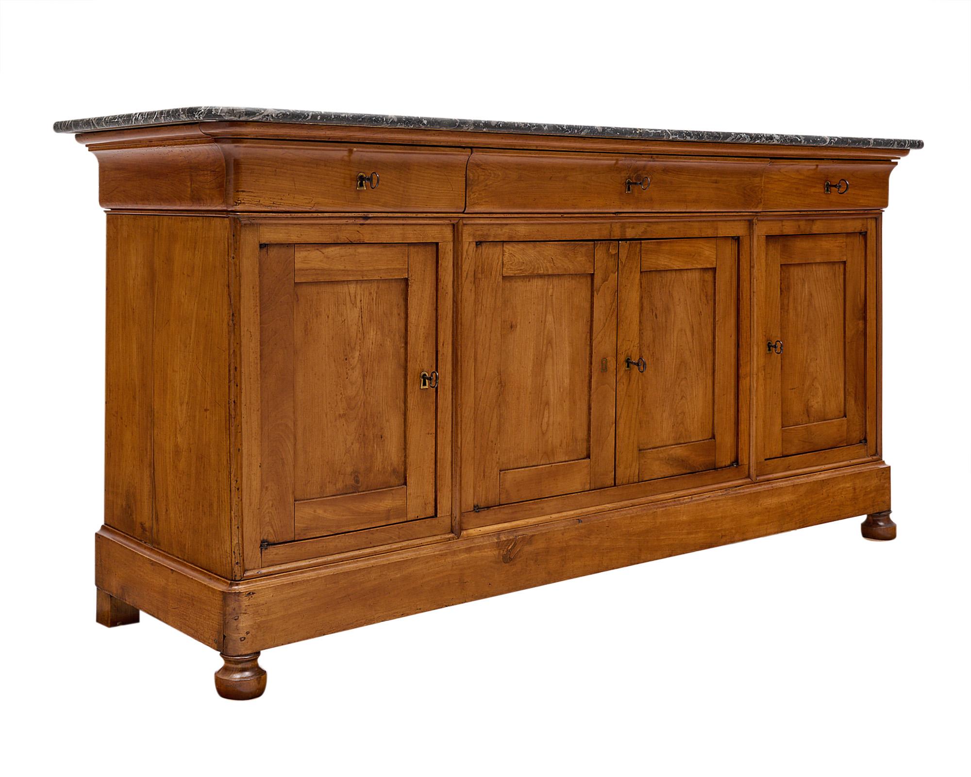 Buffet/enfilade, French, made of solid elm, from the Restauration period. Three dovetailed drawers with original locks and working keys sit atop four doors that open up to an interior shelf. The period credenza features finely hand carved trims