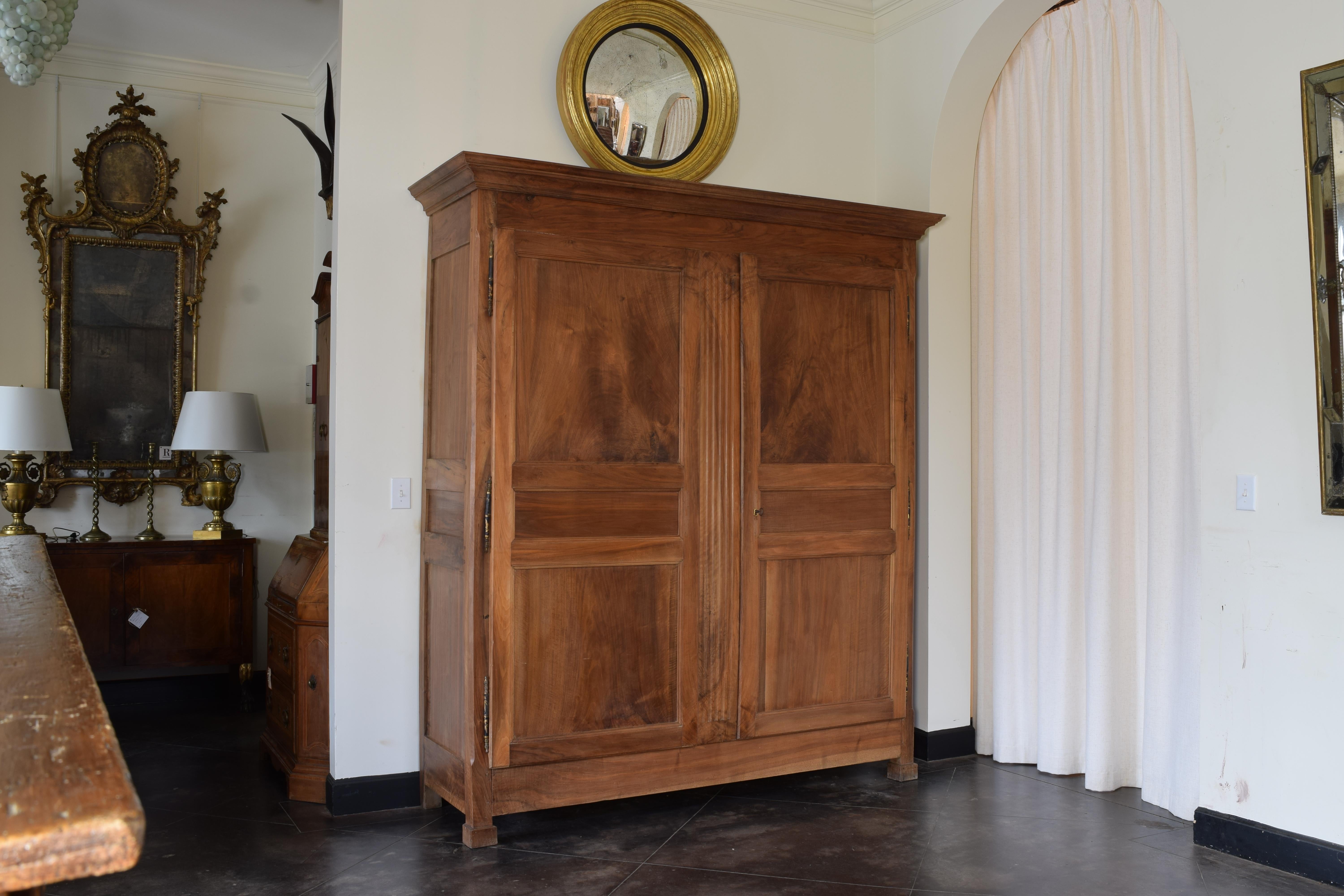 Having a boldly flared cornice atop a rectangular case fitted with a pair of large paneled doors (one including the reeded divider) flanked by paneled sides, retaining original lock and key, raised on block feet with molded detail