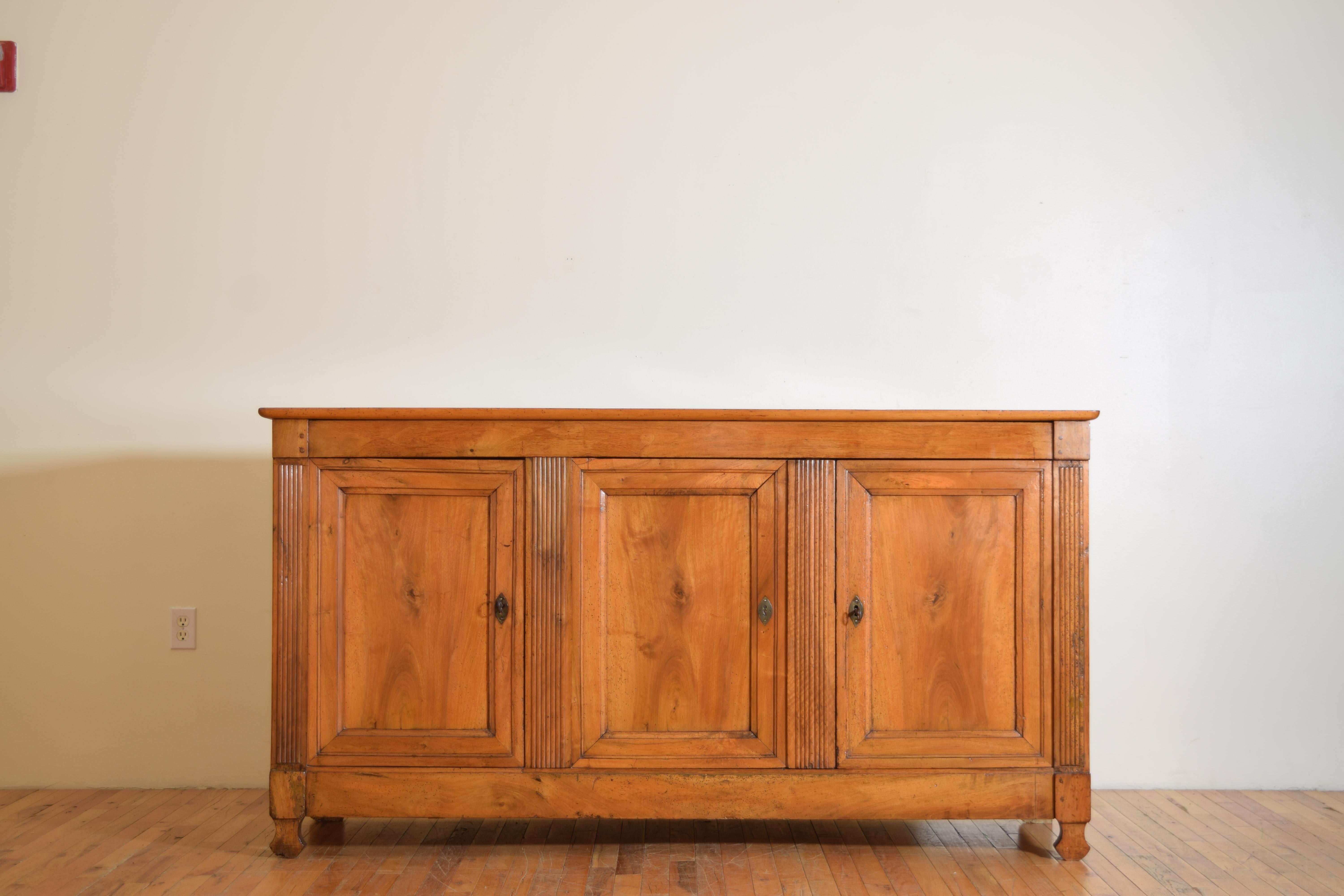 en noyer blond, avec un plateau rectangulaire en boiserie au-dessus d'une caisse conforme avec  trois portes abritant des étagères intérieures et (plus tard) des tiroirs, la façade avec des détails de colonnes cannelées, les côtés lambrissés, le