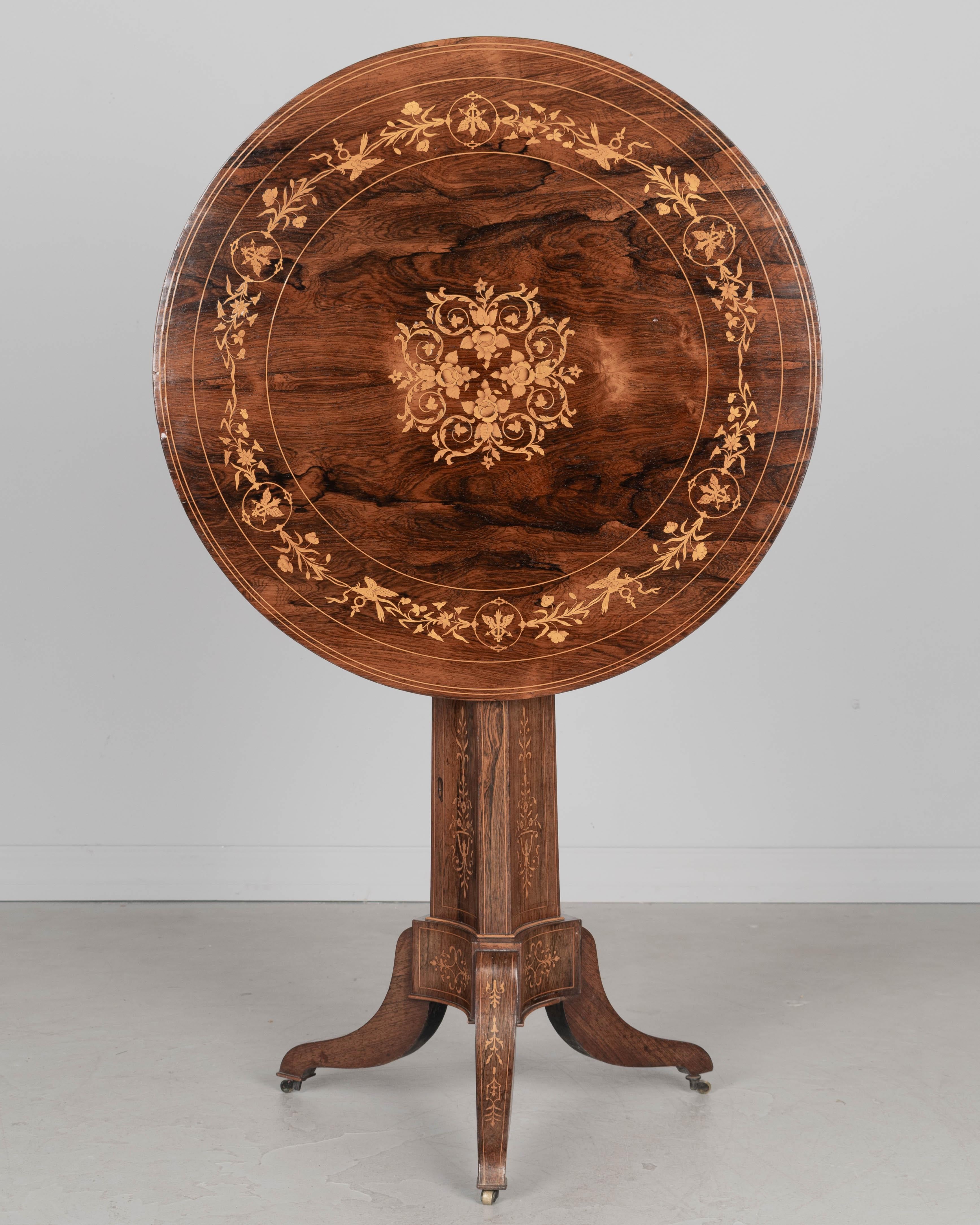Guéridon en marqueterie de style Restauration du XIXe siècle. Magnifique placage de bois de rose assorti à une marqueterie florale. La finition conserve un bel éclat. Loquet en laiton moulé sur la face inférieure. La base du piédestal a des pieds