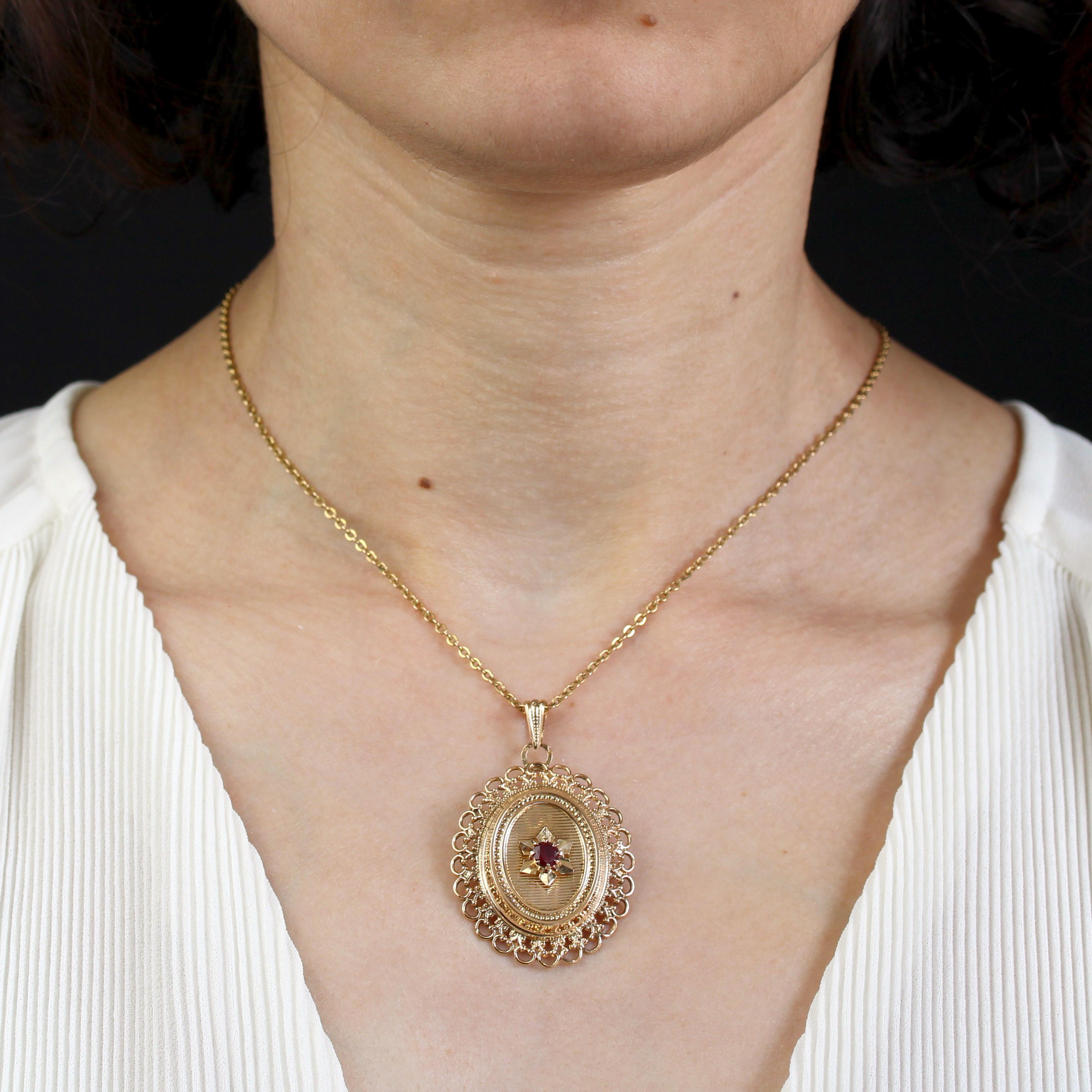 Pendant in 18 karat yellow gold, eagle head hallmark.
This vintage pendant features a claw-set round red stone in the center on a striated gold star applique. The whole forms an oval with horizontal lines, surrounded by pearled gold and a border of