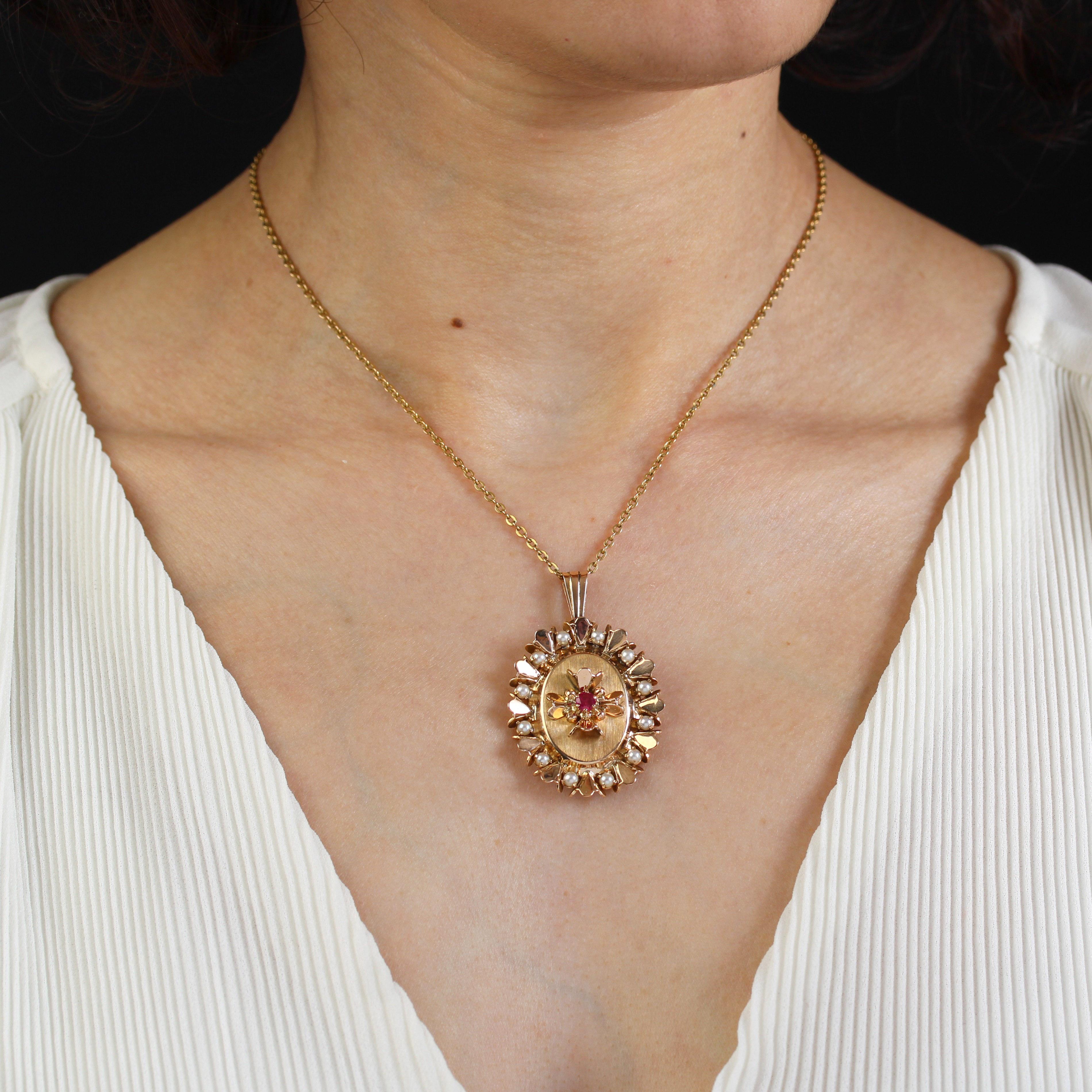 Pendant in 18 karat yellow gold, eagle head hallmark.
Antique pendant in the form of an oval satin-finish plate holding an applique flower motif adorned with a red gem in the center, whose petals are embossed. The whole is surrounded by gold petals