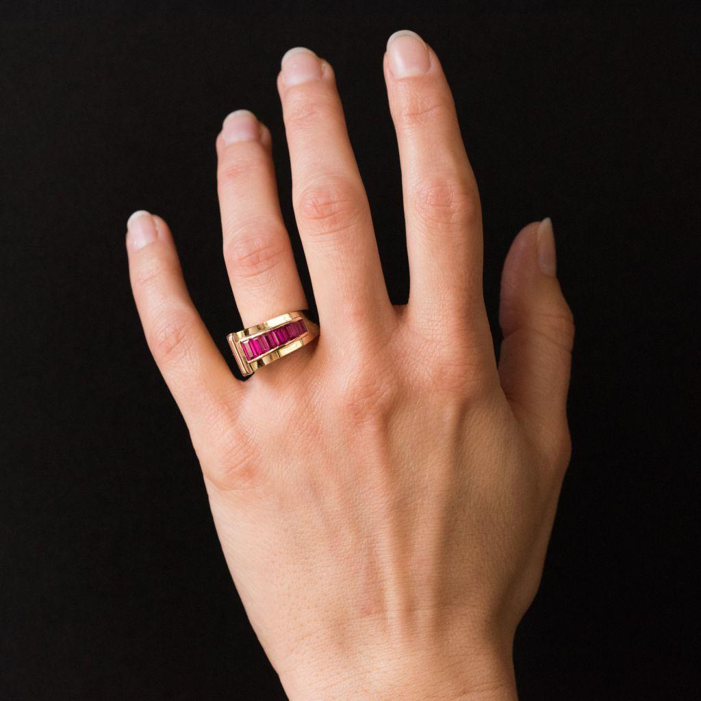 Ring in 18 carat yellow gold. 
An asymmetric tank ring set with 7 synthetic calibrated rubies in a curve. 
Maximum height : 1 cm, plate width: 1.7 cm, height on finger : 0.8 cm, ring width at the base: 4.4 mm.
Total weight of the ring :