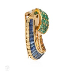 Broche française de style rétro en forme de volute, sertie de saphirs et d'émeraudes