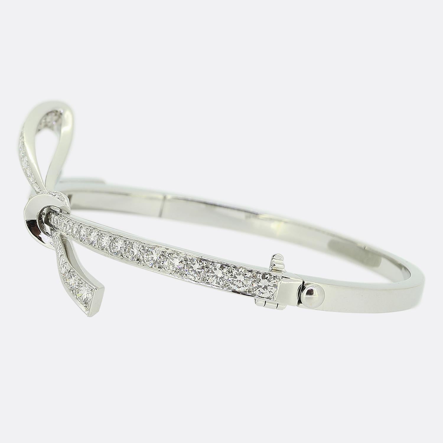 Here we have a lovely diamond bangle crafted in France from 18ct white gold. This piece showcases a ribbon styled upper section with a looping knot design which has been pavé set with 59 variously sized round brilliant cut diamonds. This