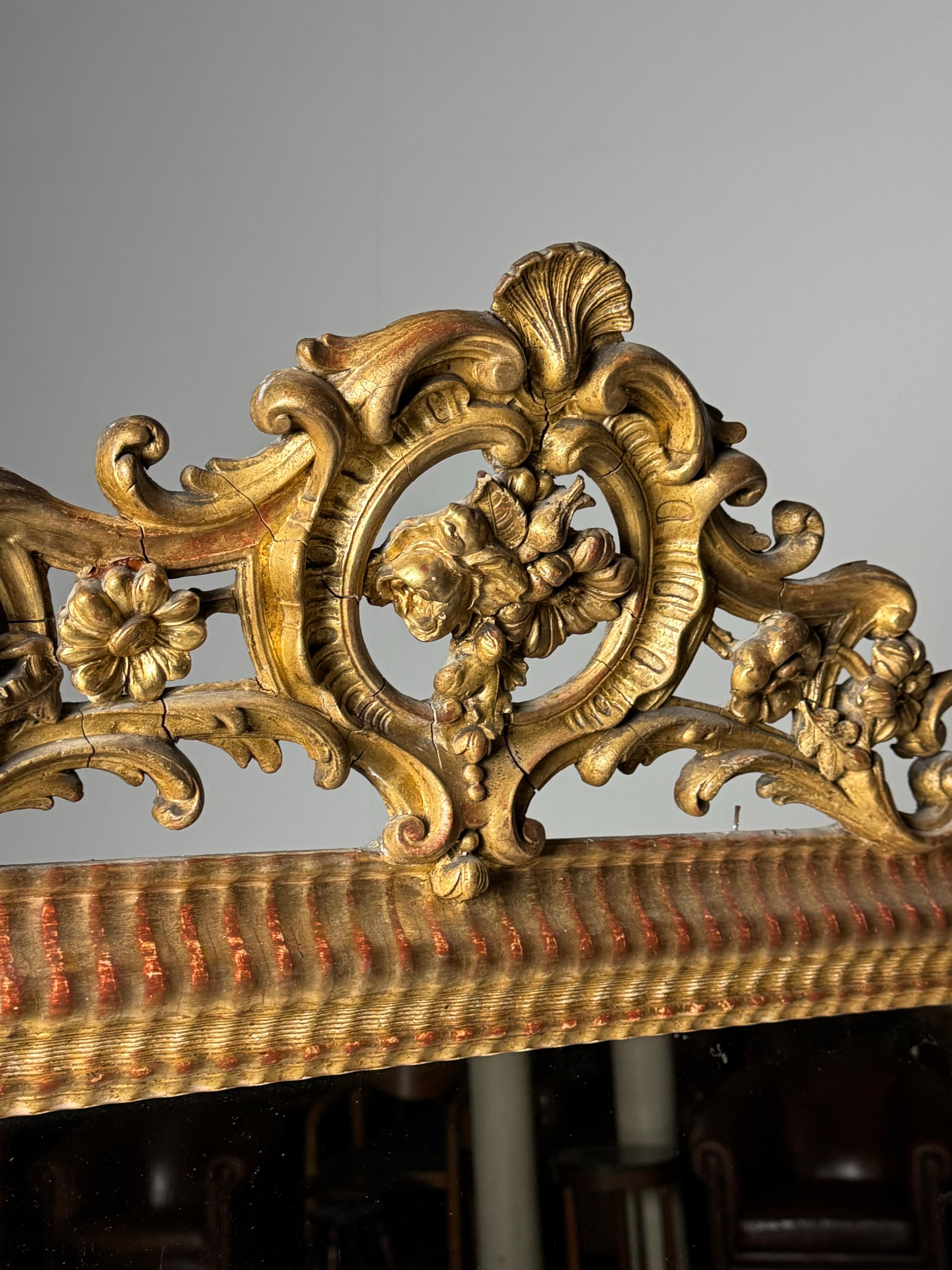 French gilt 19th century mantel mirror / crest mirror. With ribbed frame. Beautiful details with several types of flowers and shell.

In very good condition.

Dimensions: 164H x 85W x 7D