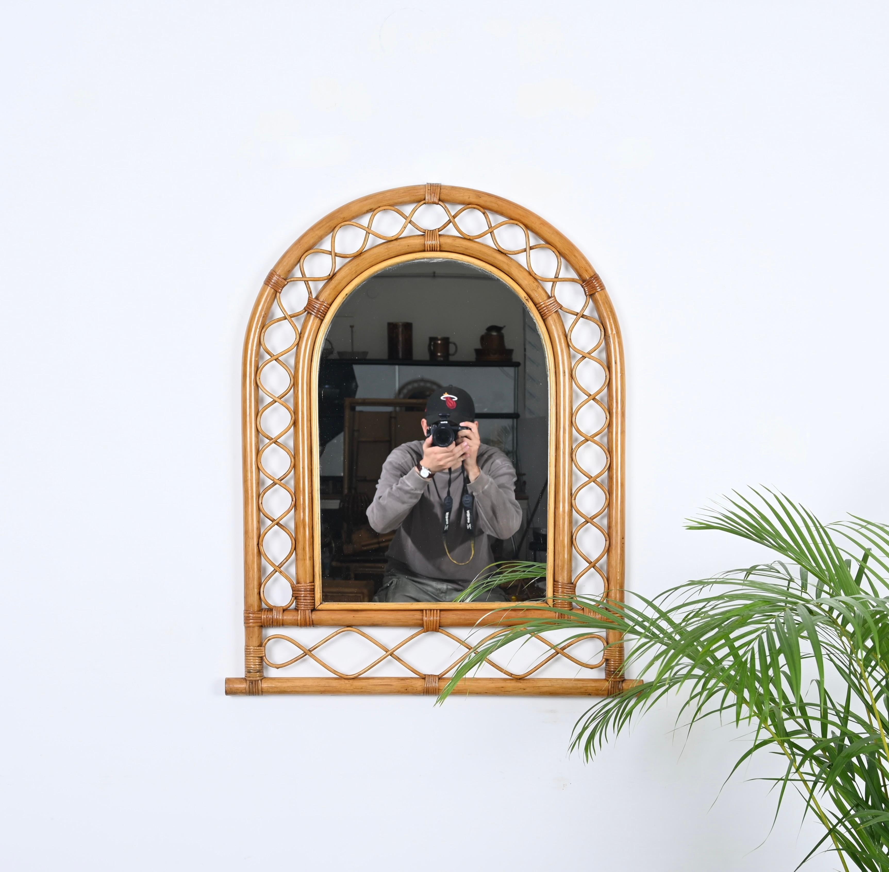 Wunderschöner bogenförmiger Wandspiegel im Côte d'Azur-Stil aus Bambus, Rattan und Weide. Dieser fantastische Artikel wurde in den 1960er Jahren in Italien hergestellt.

und dazwischen sinusförmige Verzierungen aus gebogenem Rattan. Das Ganze wird