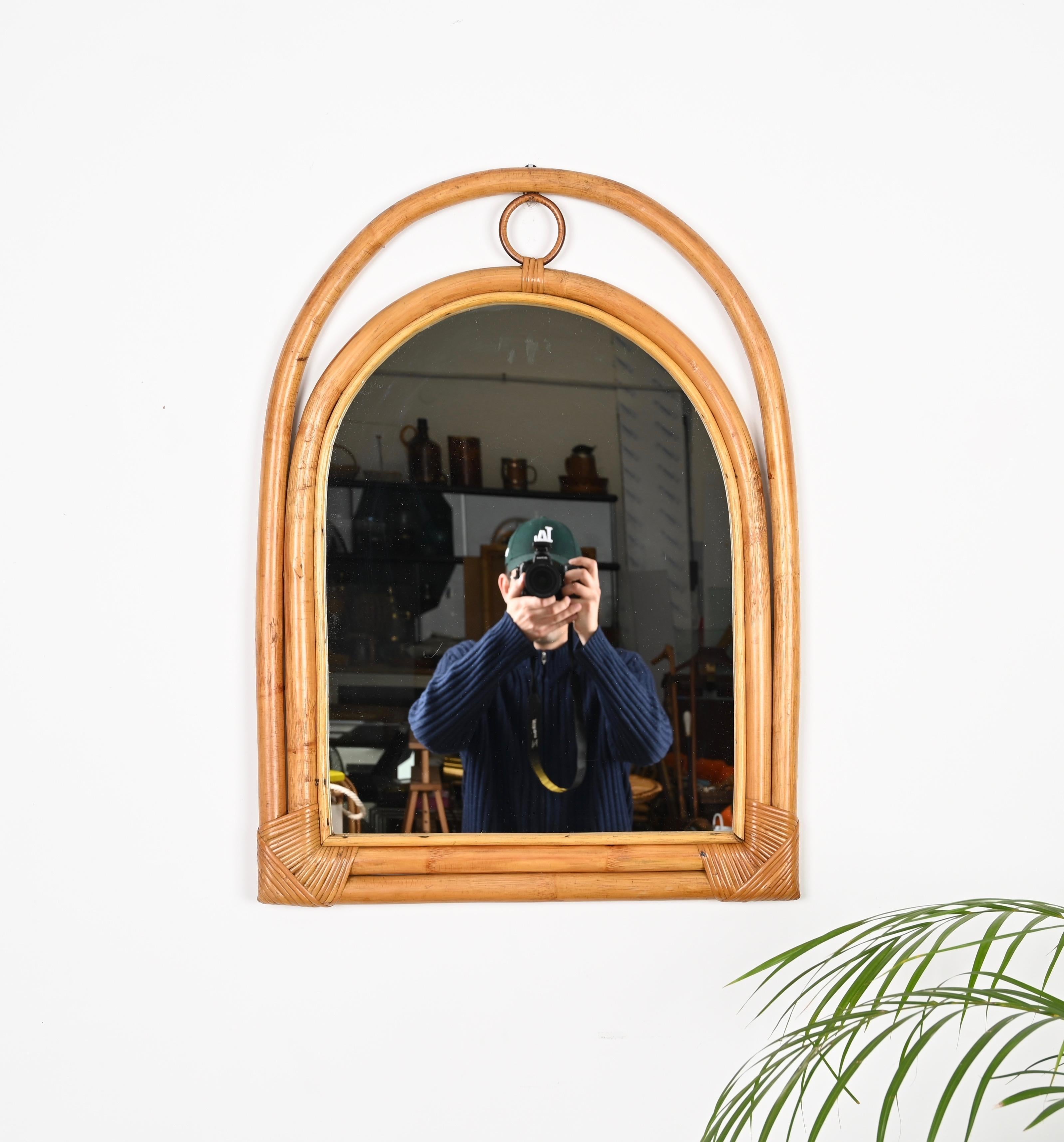 Charmant miroir en forme d'arche du milieu du siècle dernier, fabriqué en bambou, rotin et osier courbés. Ce charmant miroir de style Côte d'Azur a été fabriqué en Italie dans les années 1970. 

Ce miroir unique présente un double cadre en bambou