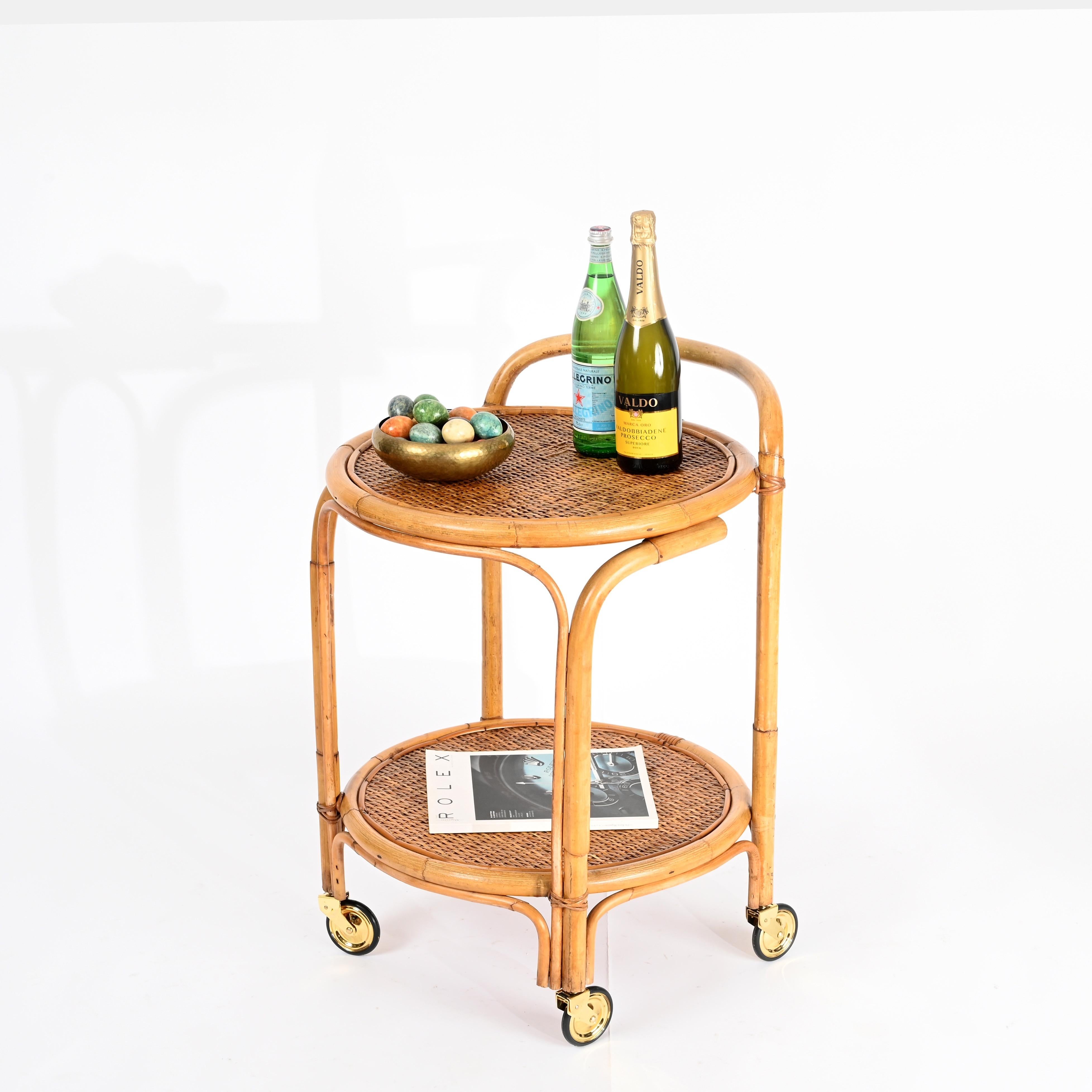 Stunning Mid-Century round bar cart entirely made of curved bamboo, rattan, and hand-woven wicker, completed with brass wheels. This incredibly stylish organic cart was produced in Italy during the 1960s.

In amazing condition and featuring a