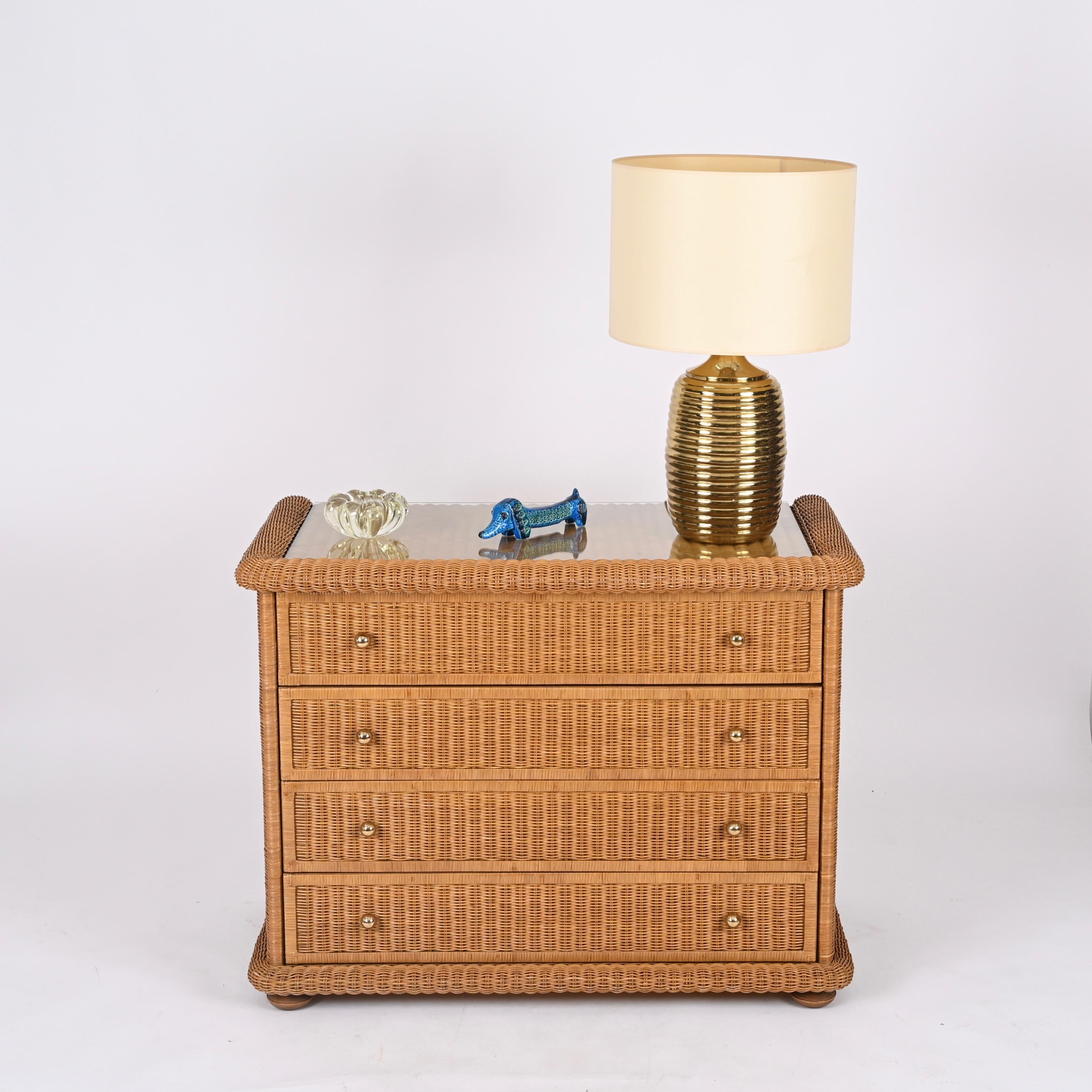 Stunning Mid-century French Riviera style chest of drawers fully made in woven rattan with brass knobs and a top crystal glass. This incredibly charming piece was made by Vivai del Sud, in Italy during the 1970s. 

The key feature of the beauty of