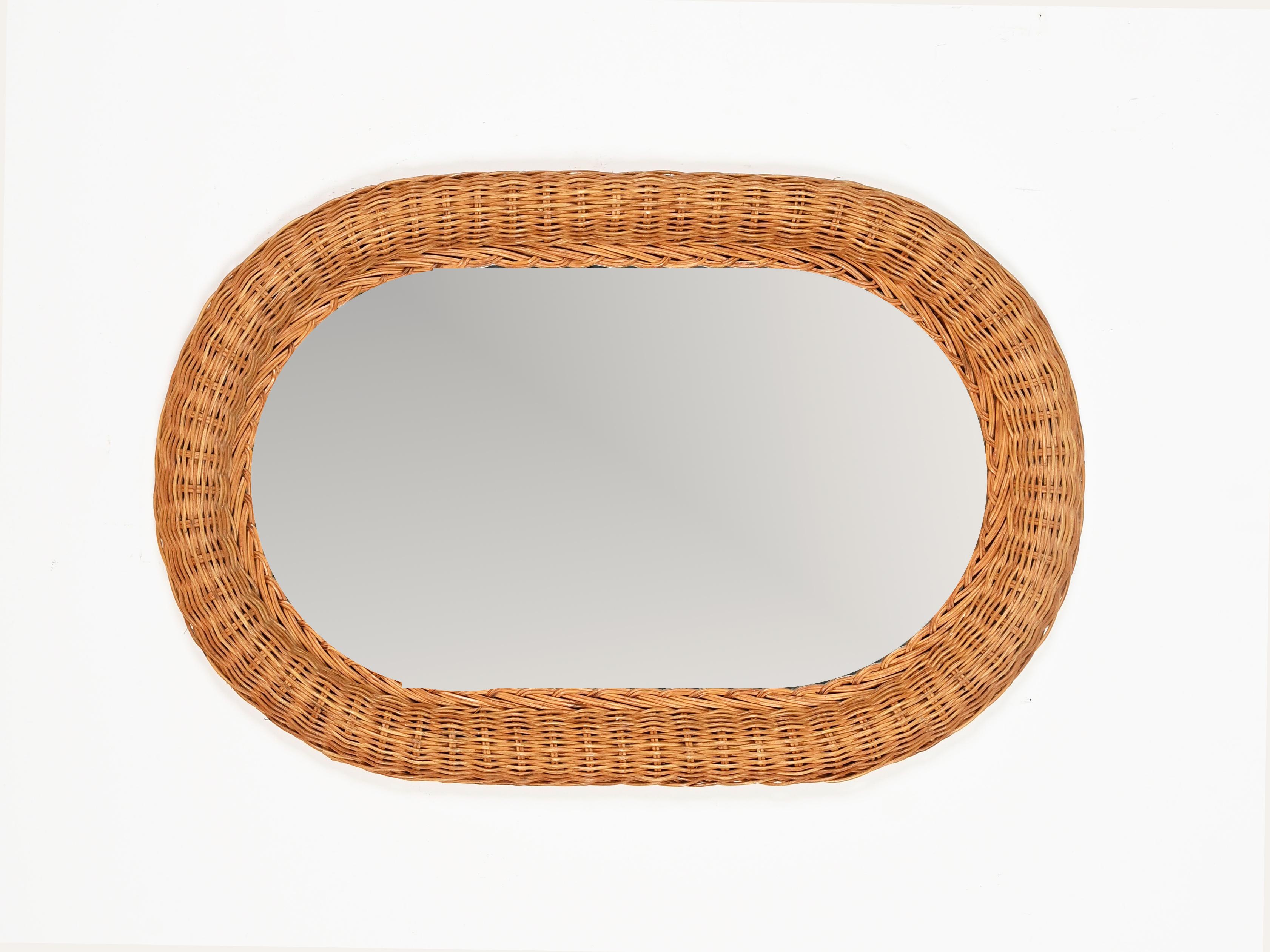Stunning mid-century organic oval mirror completely made in hand-woven rattan wicker. This gorgeous French Riviera style mirror was designed in Italy during the 1970s.

In fabulous condition and with a charming honey color, this mirror has a oval