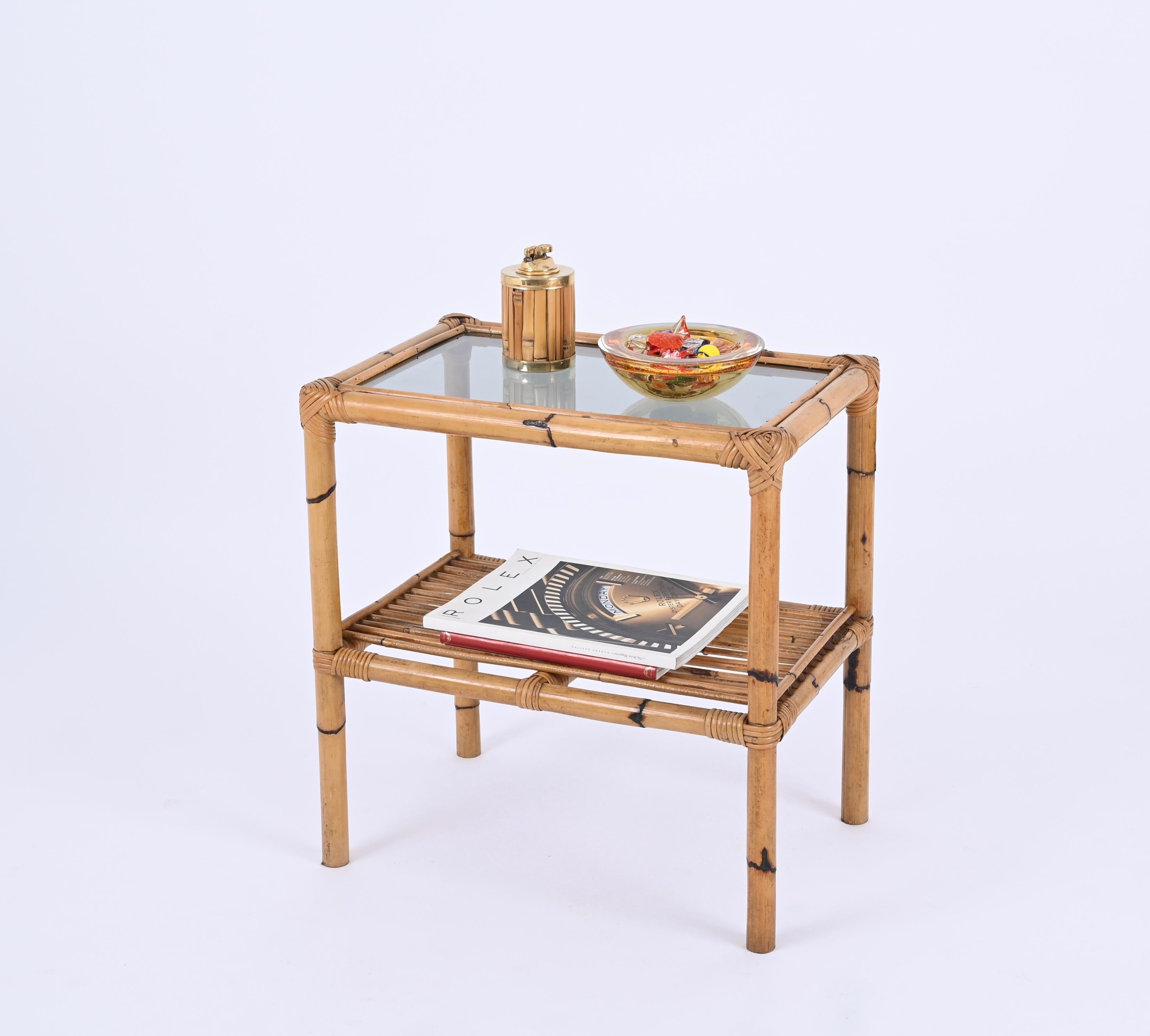 Wunderschöner Nachttisch oder Beistelltisch aus Bambus und geflochtenem Rattan mit Glasplatte. Dieser schöne zweistöckige Tisch wurde in den 1970er Jahren in Italien entworfen.

Dieses atemberaubende Stück ist vollständig aus Bambusrohren