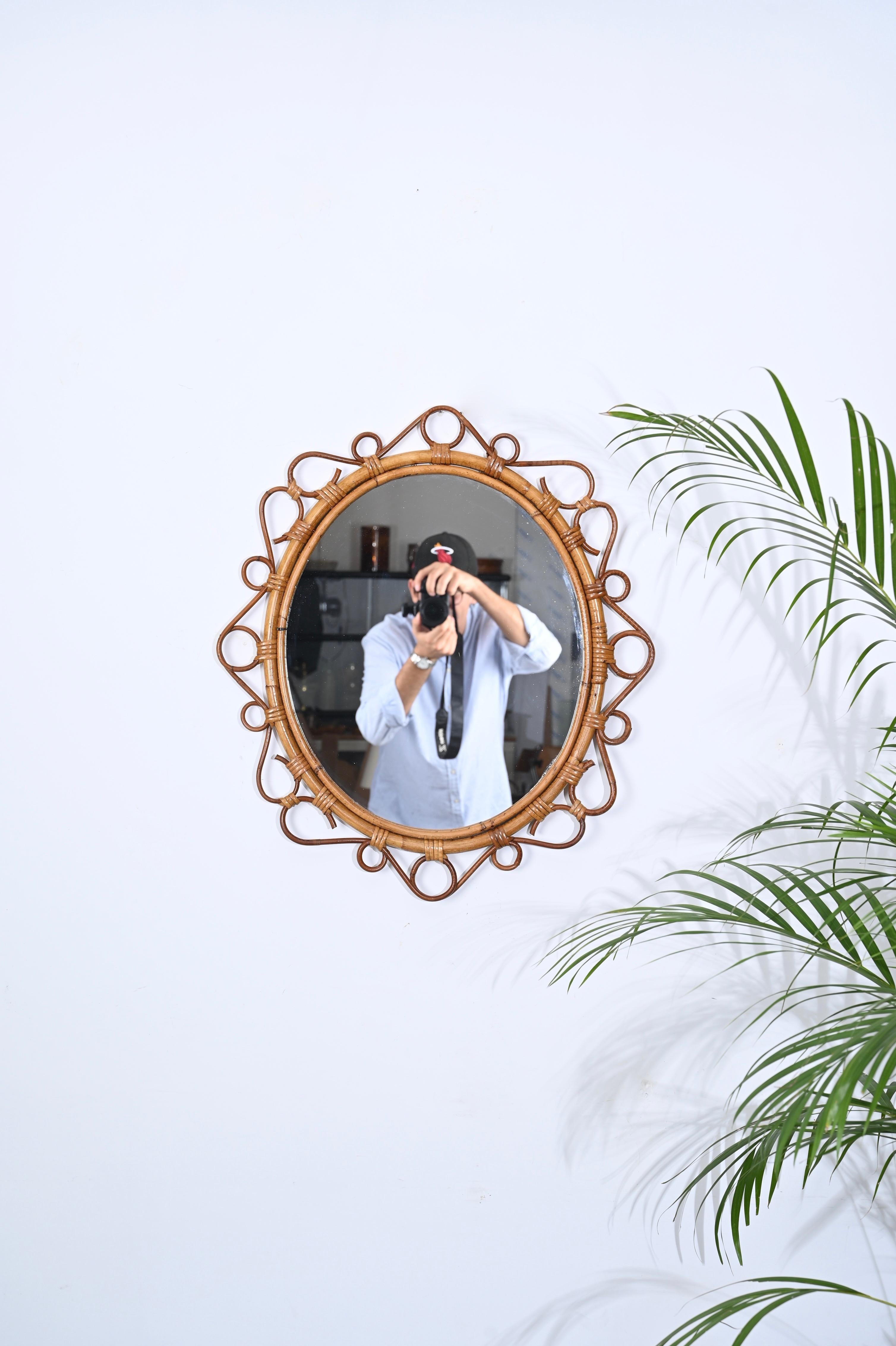 Stunning Mid-Century oval wall mirror in curved bamboo, rattan and wicker. This lovely Cote d'Azur style mirror was designed in Italy during the 1970s.

This unique mirror features a double oval frame in bamboo that is embellished by stunning