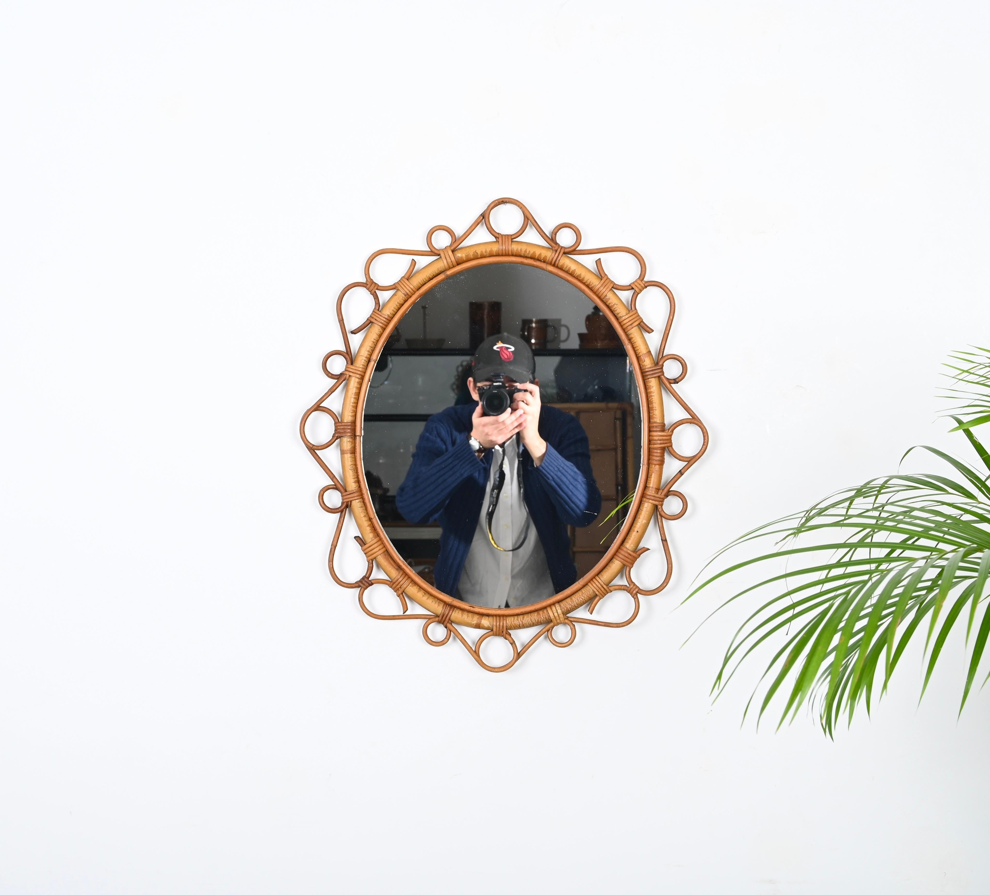 Stunning Mid-Century oval wall mirror in curved bamboo, rattan and wicker. This lovely Cote d'Azur style mirror was designed in Italy during the 1970s.

This unique mirror features a double oval frame in bamboo that is embellished by stunning