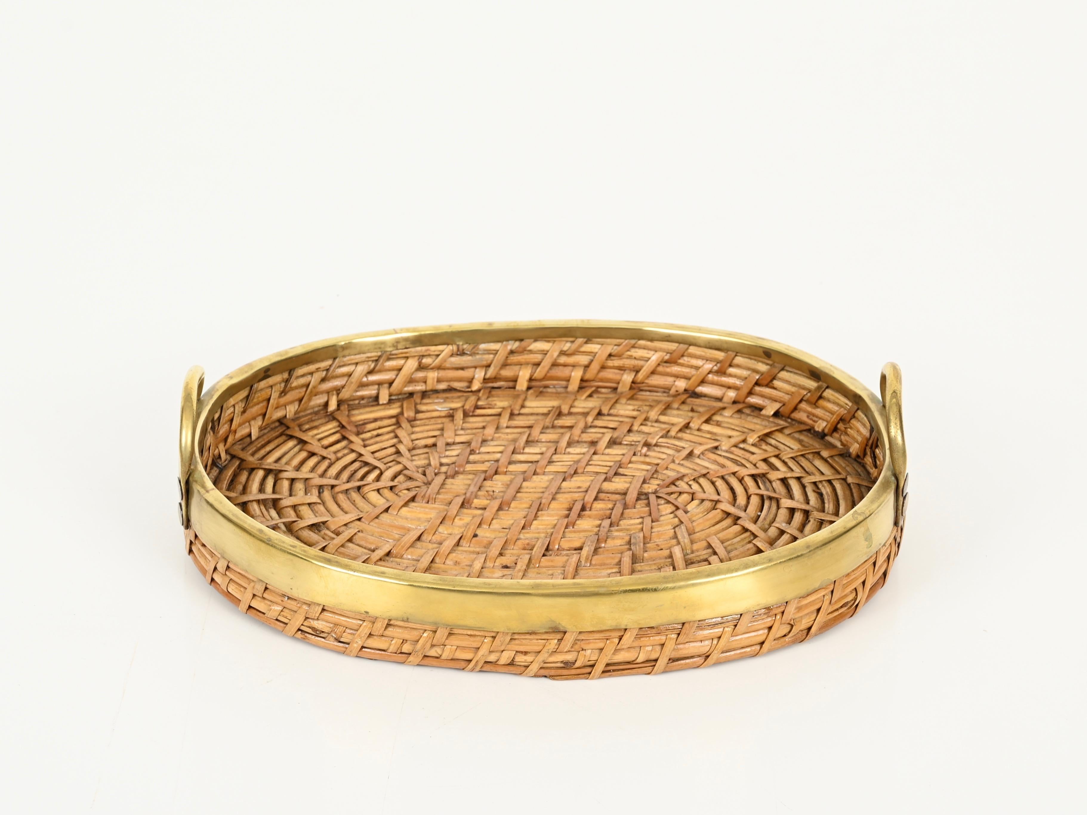 Gorgeous Mid-Century organic centerpiece or vide-poche fully made in rattan, hand-woven wicker with a brass rim and handles.
This stylish French Riviera style tray was designed in Italy during the 1970s, clearly in the style of a Gabriella Crespi