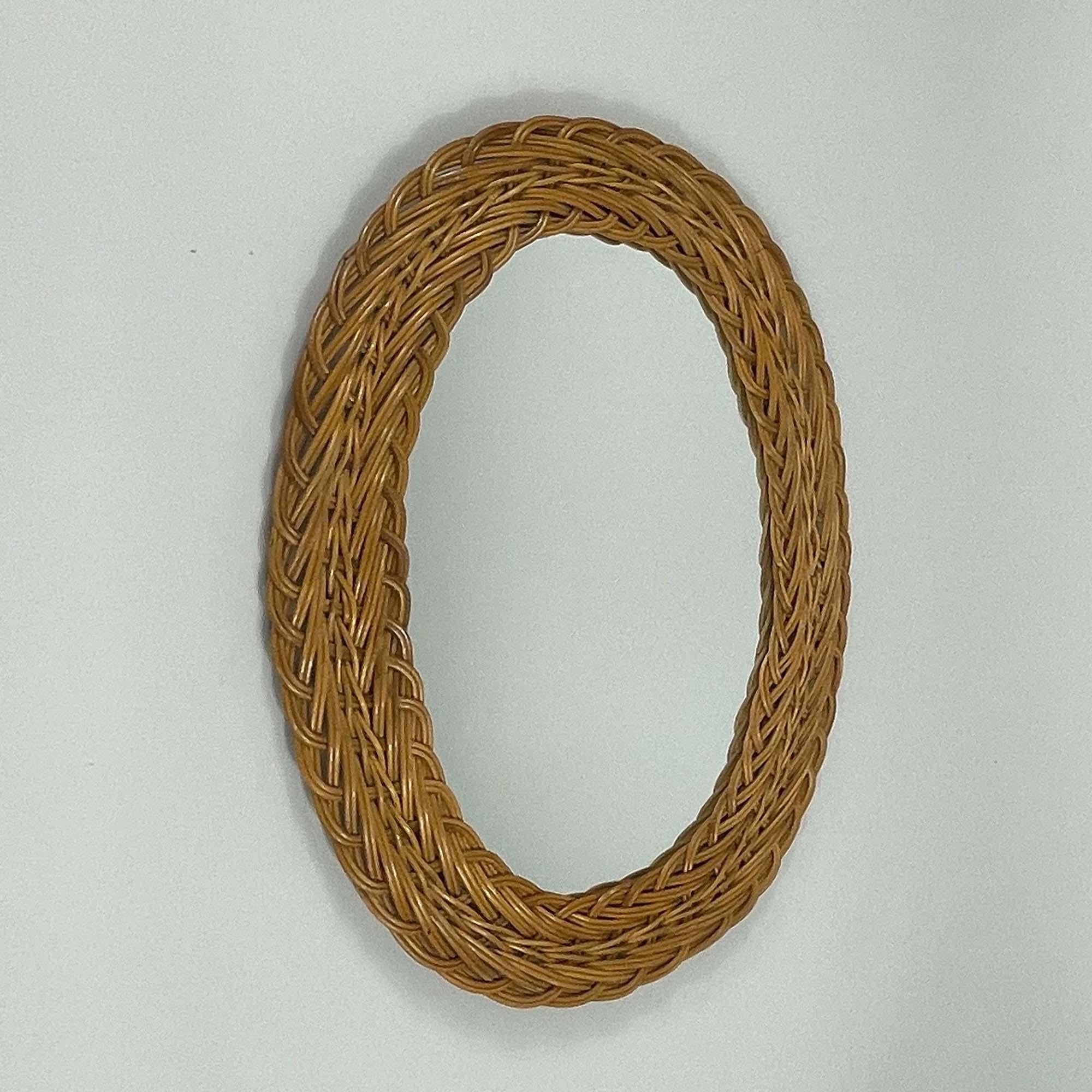 This mid-century French Riviera style wall mirror was designed and manufactured in France in the 1960s. 

The rattan frame has a braided pattern, giving it a textured and handcrafted appearance. The rattan's natural color adds a warm, vintage